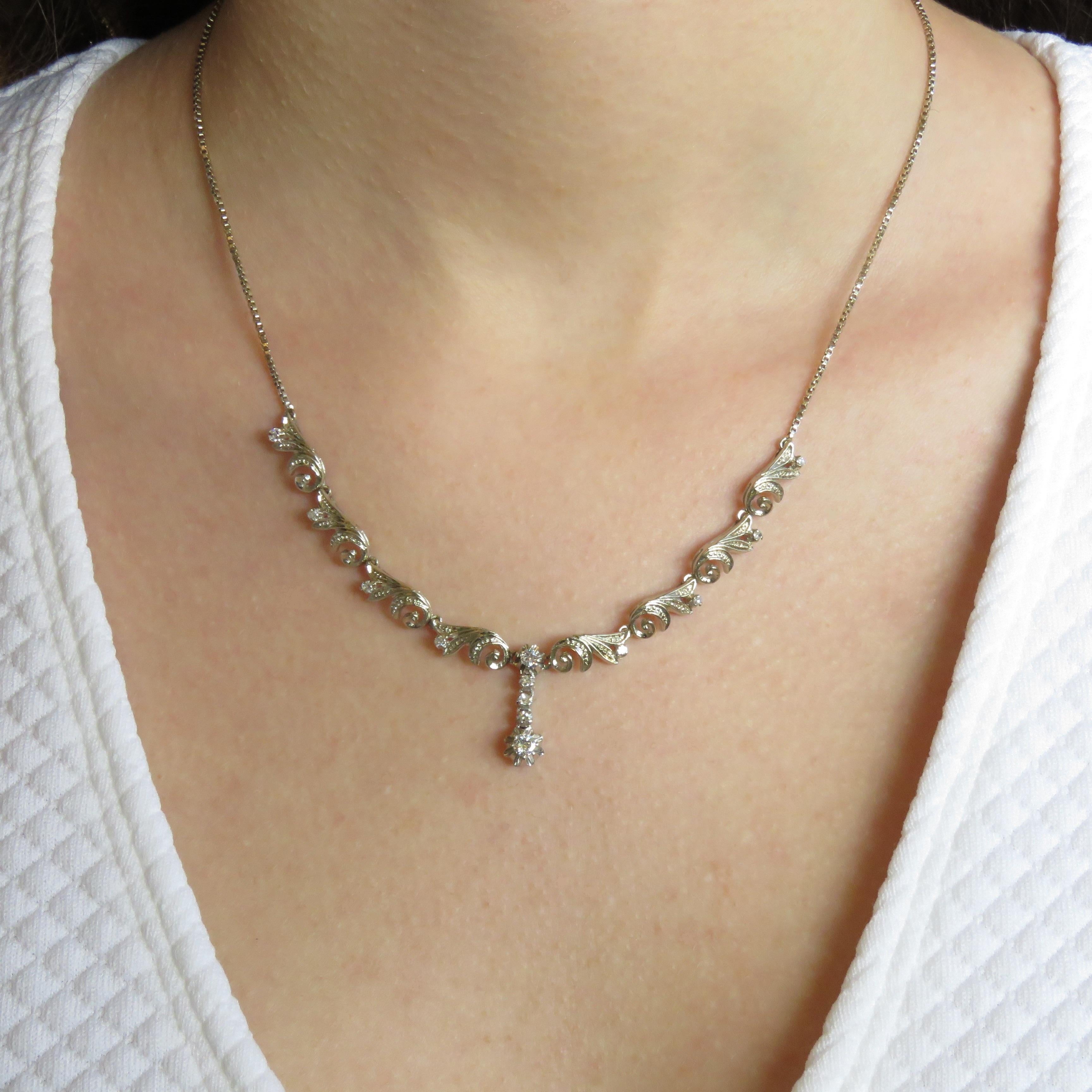 This elegant retro necklace in 18 karat white gold features one central diamond 0.10 ctw shining with twelve white diamonds 0.30 ctw circa.
The total length of the necklace is  440 millimeters / 17.322 inches. This item is stamped with the Italian