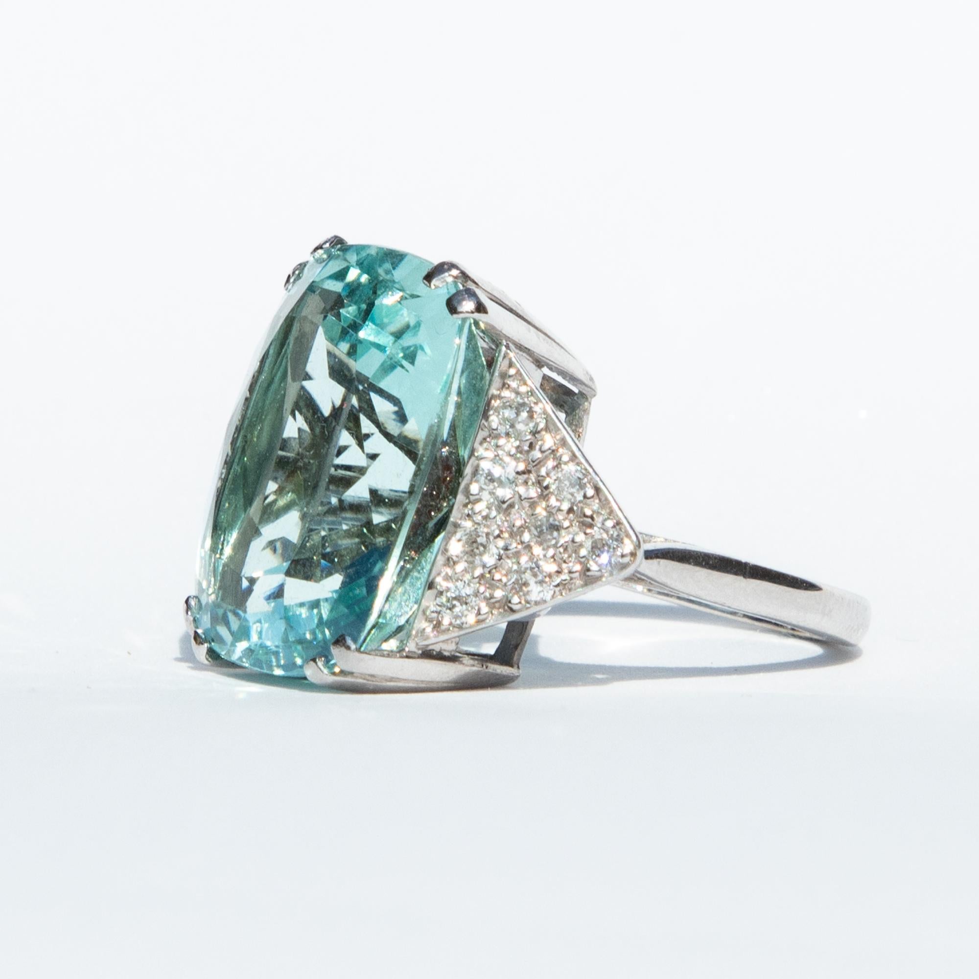 A wonderful ring from the 1960s. The large central Aquamarine weighs in excess of 20 carats, and is surrounded by diamonds in a triangular 18 karat white gold setting.

Ring size J 1/2 or 5. 