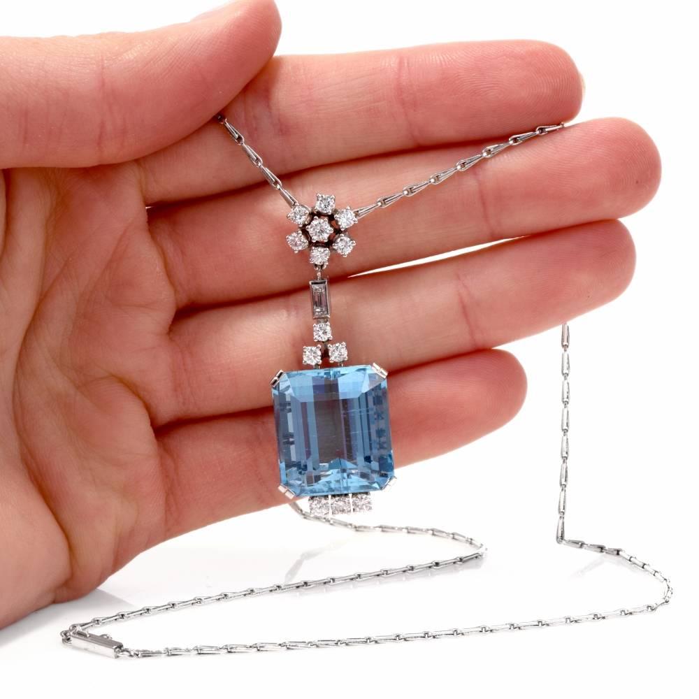 This vintage 1960's aquamarine pendant with diamond profiles and integrated chain is crafted in 18-karat white gold, exposidng a prominent 22.80 carat very fine aquamarine measuring 18.2 mm x 16.5 mm. It is mounted within a highly ornate, openwork
