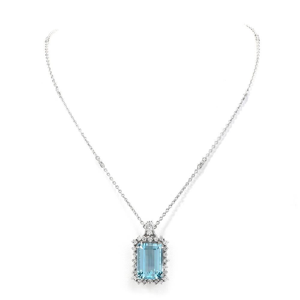 This estate 1970's aquamarine pendant with diamond profiles and integrated chain is crafted platinum, exposidng a prominent approx. 25.21 carat very fine natural aquamarine measuring 20.3mm x 14.0mm x 10.3mm. It is mounted within a highly ornate,