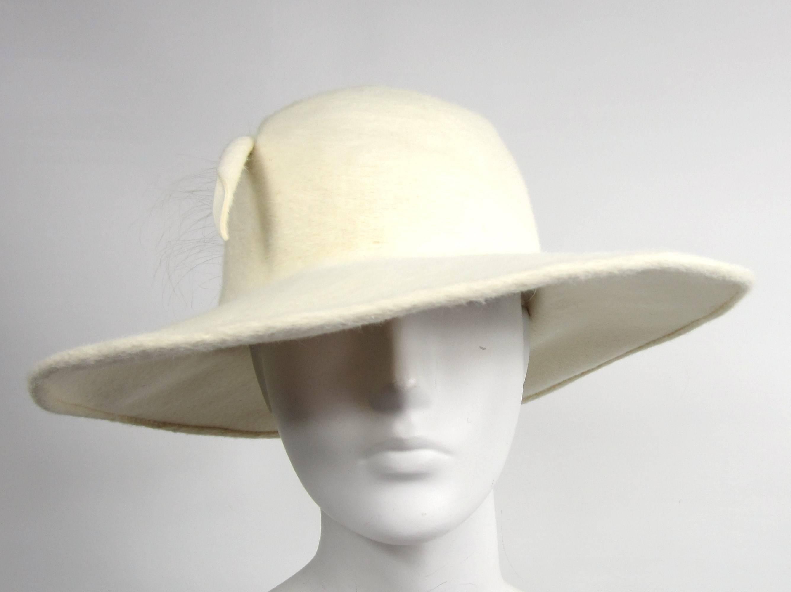 Cream-colored Wide Brim hat by Archie Eason. 4 inch Brim at the widest point.  Large Plum Feather makes a statement on this hat. Measuring 22-3/4 in inside circumference- Approx. 7-1/4 hat size. We have hundreds of New Never Worn items on our