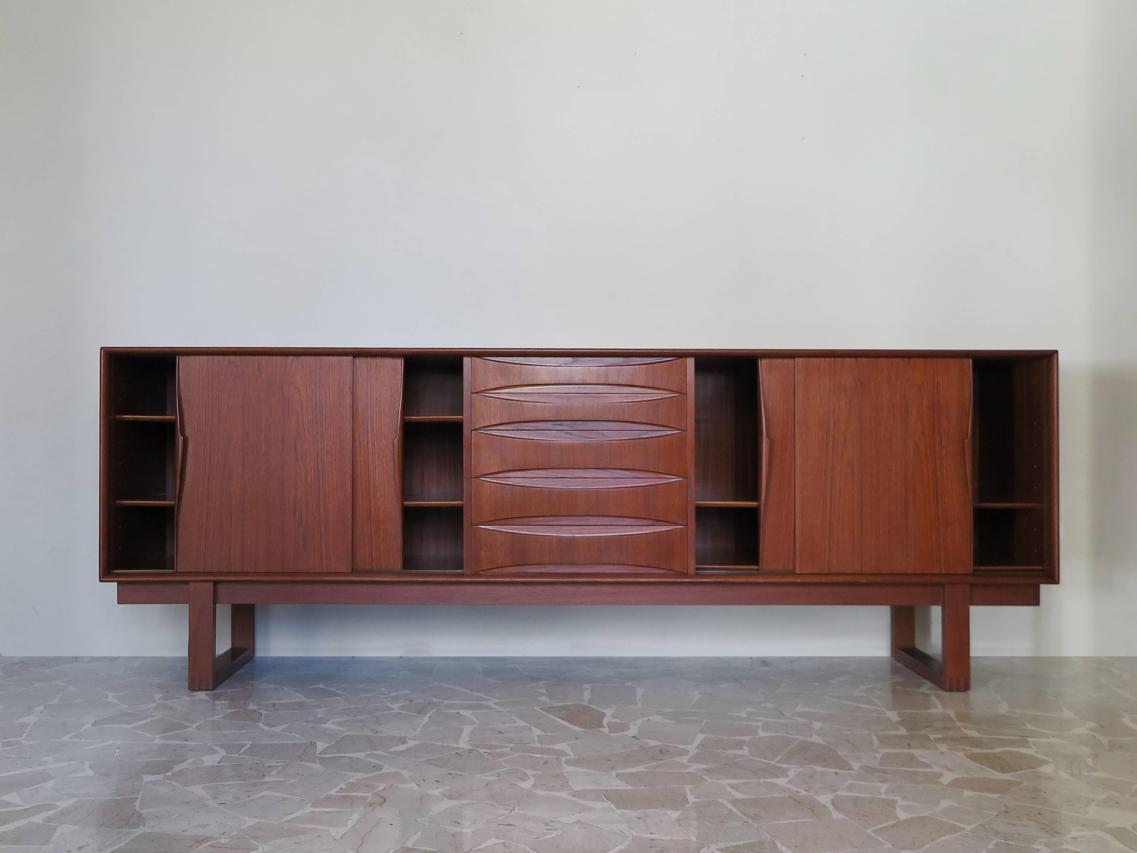 Famous Danish and midcentury design teak sideboard designed by Arne Vodder with five drawers and four sliding drawers enclosing adjustable shelves.