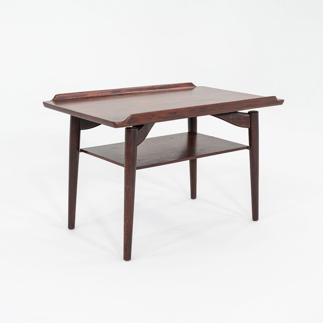 Il s'agit d'une table d'appoint T9, conçue à l'origine par Arne Vodder pour George Tanier. Cet exemple particulier a été produit au Danemark et date des années 1960. La table est composée de teck et de chêne. Les bois contrastés soulignent