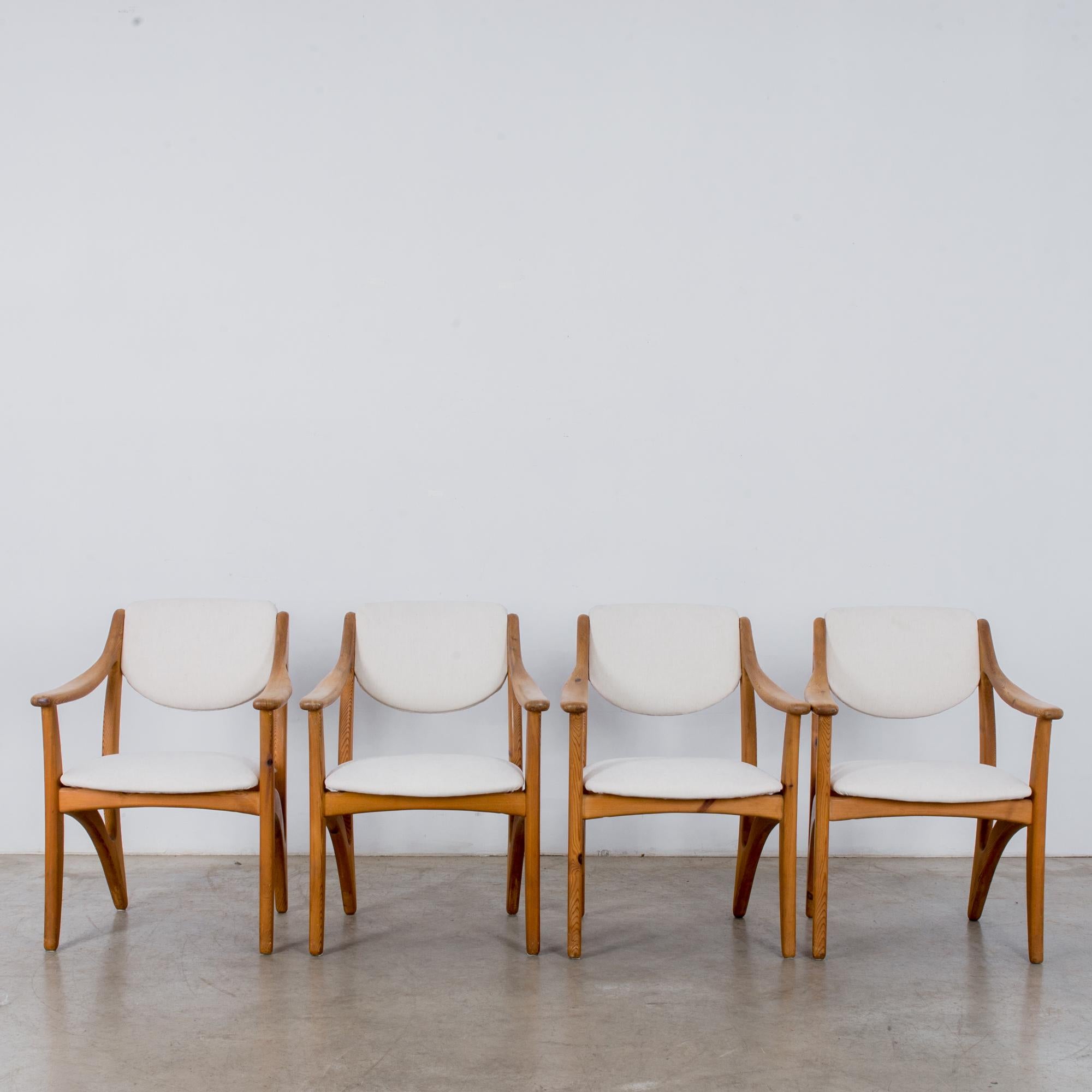 This set of armchairs designed by Arne Vodder was made in Denmark, circa 1960. The upholstered cream backrests and seats complement the beautiful grain of the light, polished wood. The armrests and side stretchers of this timeless and elegant set of