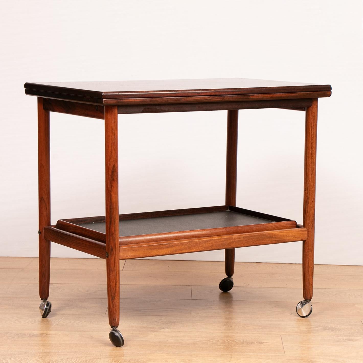 1960s Arrebo Møbler Danish rosewood folding top serving trolley or drinks/bar cart. Rare to find with a wonderful rosewood deep grain and patina.

The serving cart has a unique feature folding tabletop with brass feature fittings which turns on