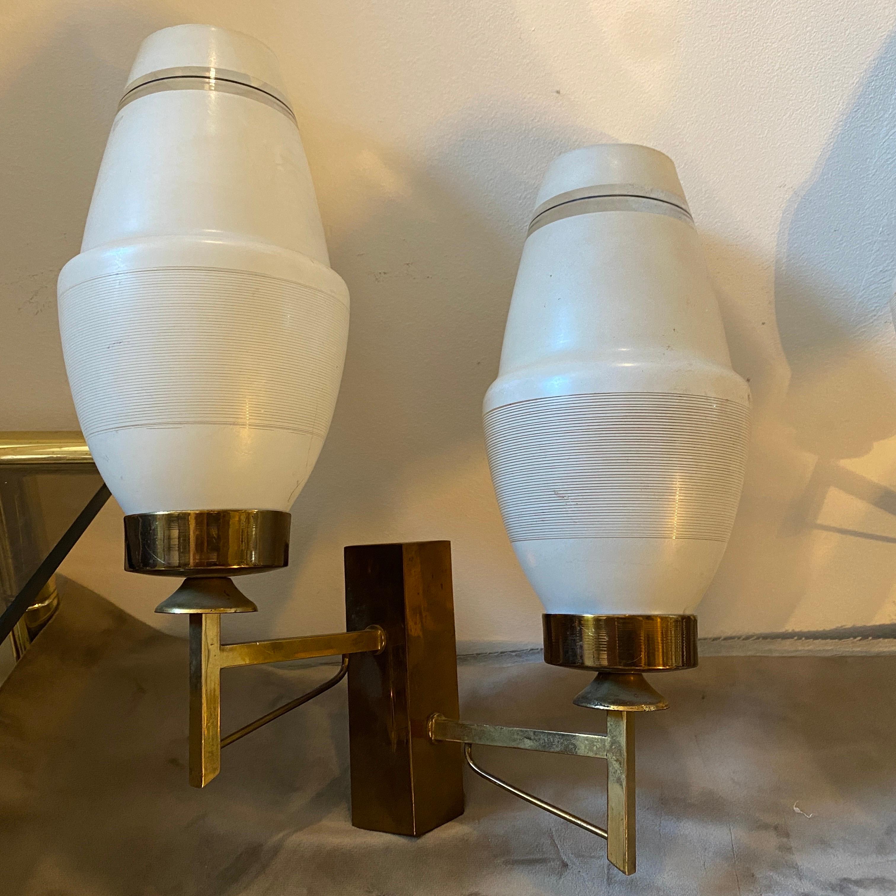 A pair of Mid-Century Modern solid brass and glass wall sconces designed and manufactured in Italy in the 60s in the manner of Arredoluce. They work both 110-240 volts and need regular e14 bulbs. Small defect on brass visible in the photos.