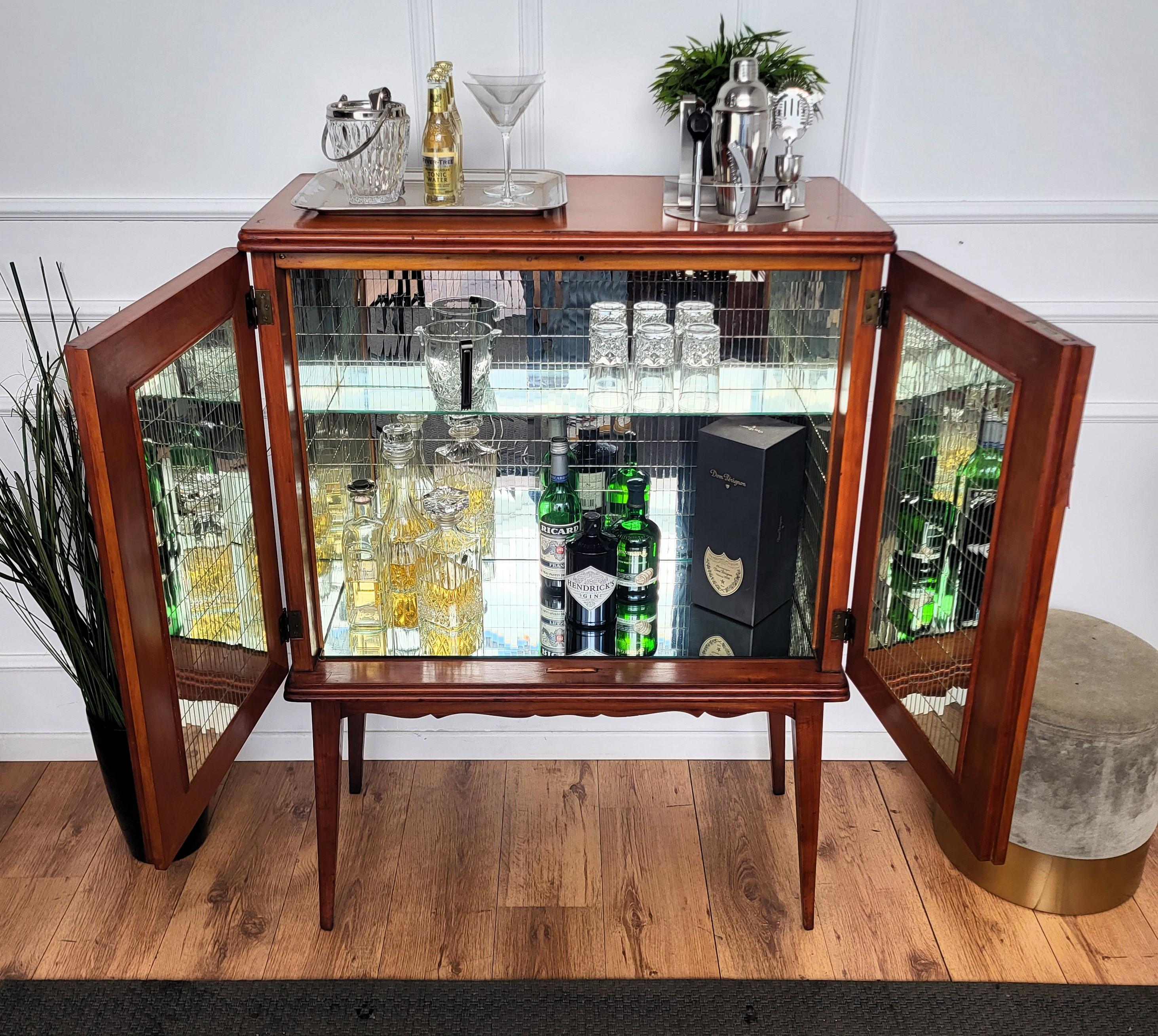 Unique and very elegant Italian Art Deco Mid-Century dry bar cabinet, in walnut with double front door having amazing interior part with mirrors and a two-tier side bottle holders. The piece is highlighted by the typical frontal inlay decors and the