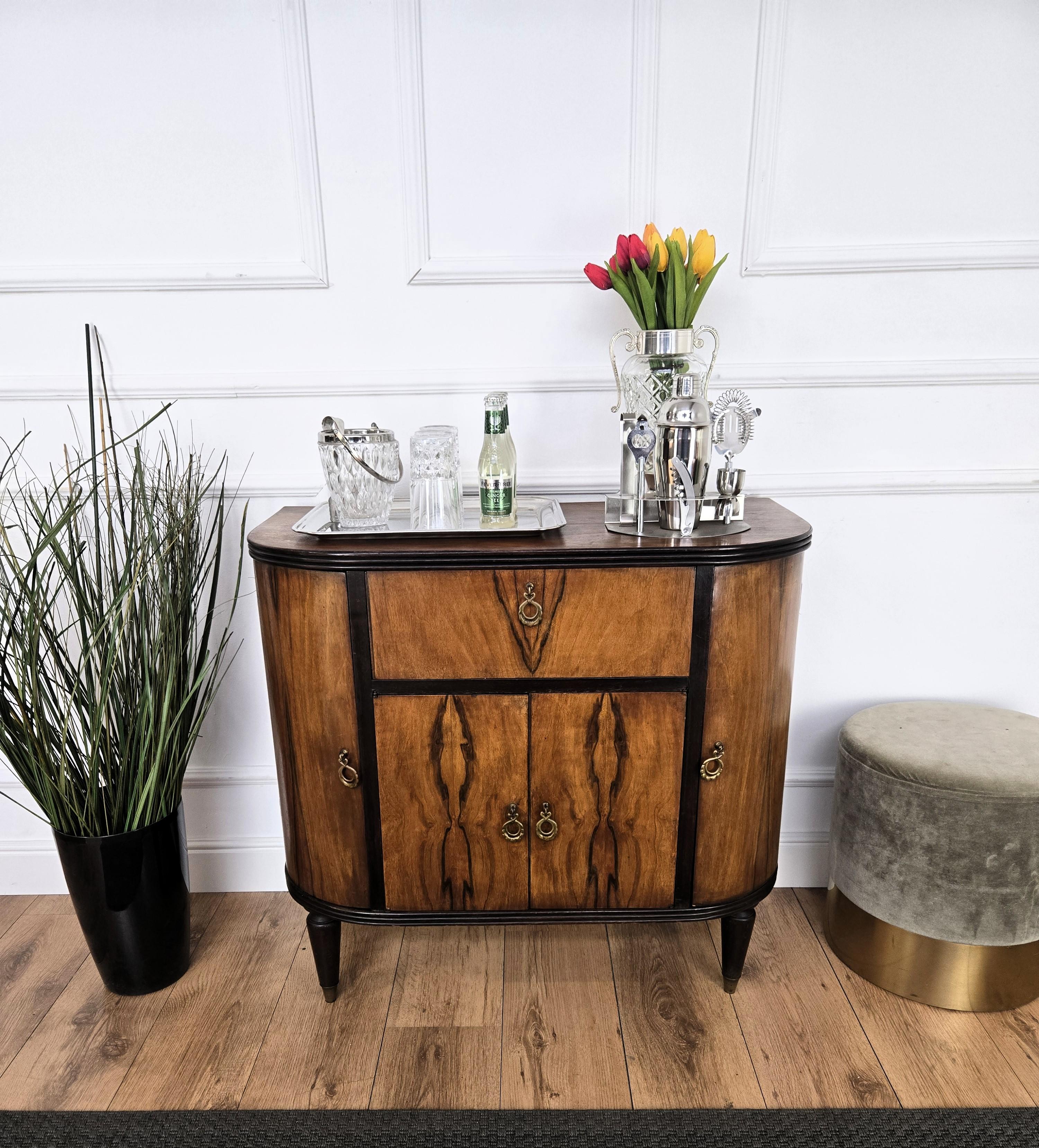 Beautiful Italian Art Deco Mid-Century Modern dry bar cabinet decorated in various veneer briar burl wood, with two side doors, central slant door and antique brass handles. When opened, on the sides we have bottles storage space while in the center