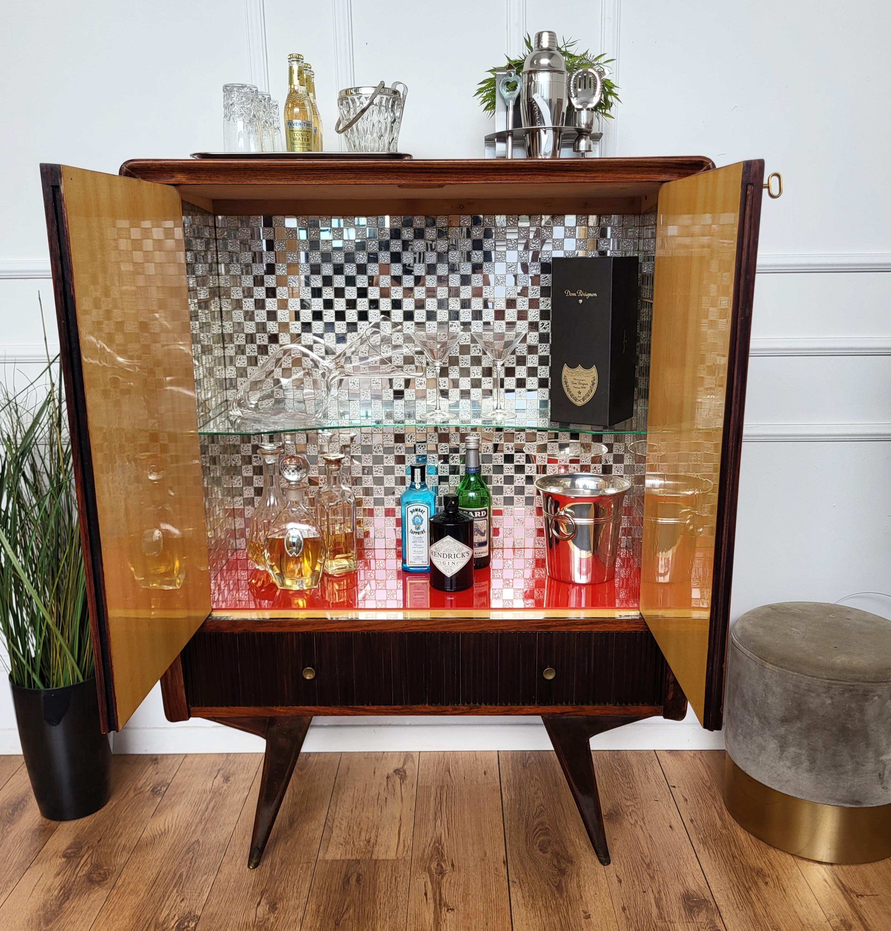 Eleganza e raffinatezza: mobile da cocktail bar in stile Art Deco Mid-Century Modern, in noce, con doppia porta d'ingresso e una sorprendente parte interna con specchi. Il pezzo è evidenziato dai tipici decori frontali in legno impiallacciato, dai