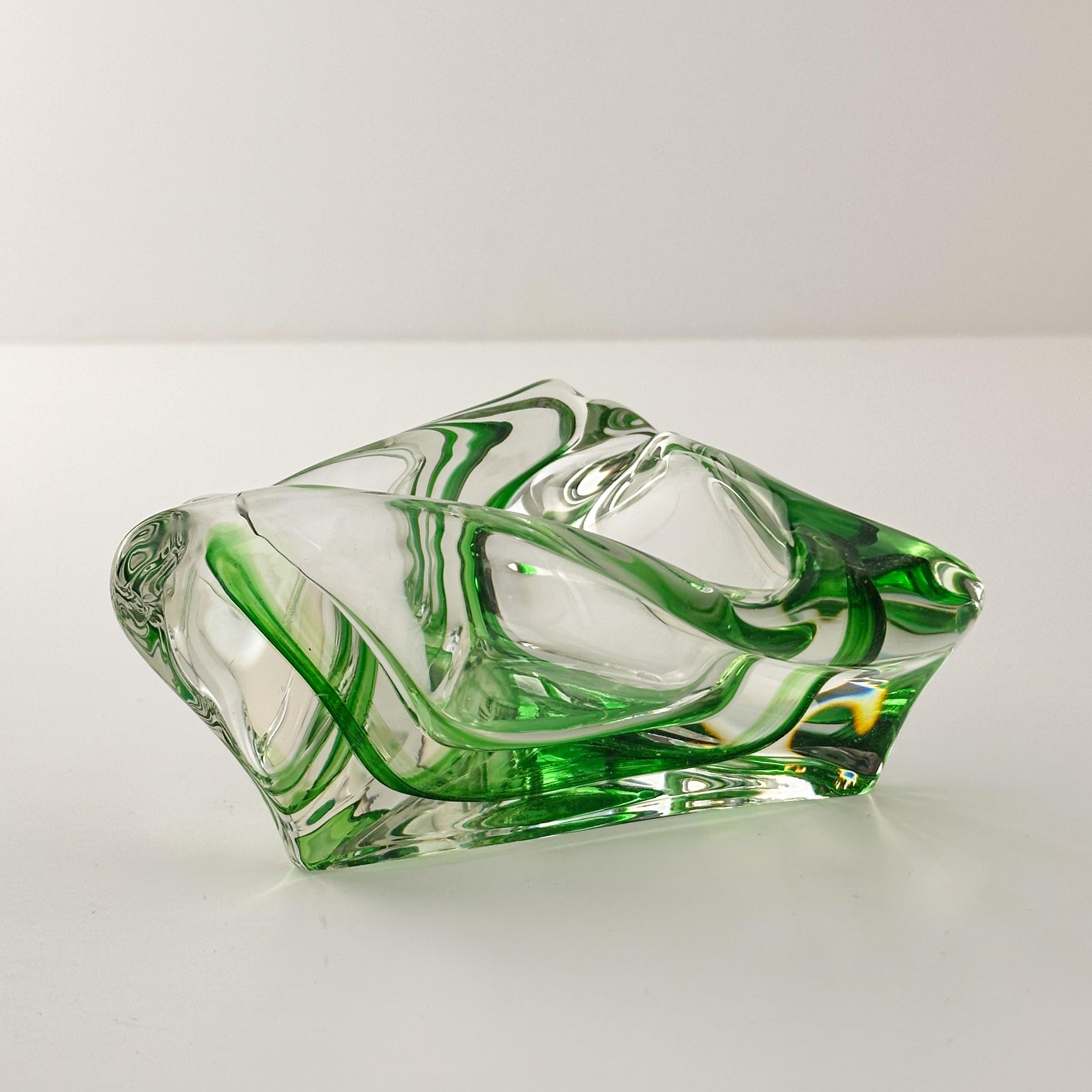 A sculptural handcrafted art glass dish attributed to Max Verboeket for Kristalunie Maastricht, circa 1960s.

This striking piece features a triangular form with thick, clear glass walls accented by fine ribbons of transparent green glass. Each