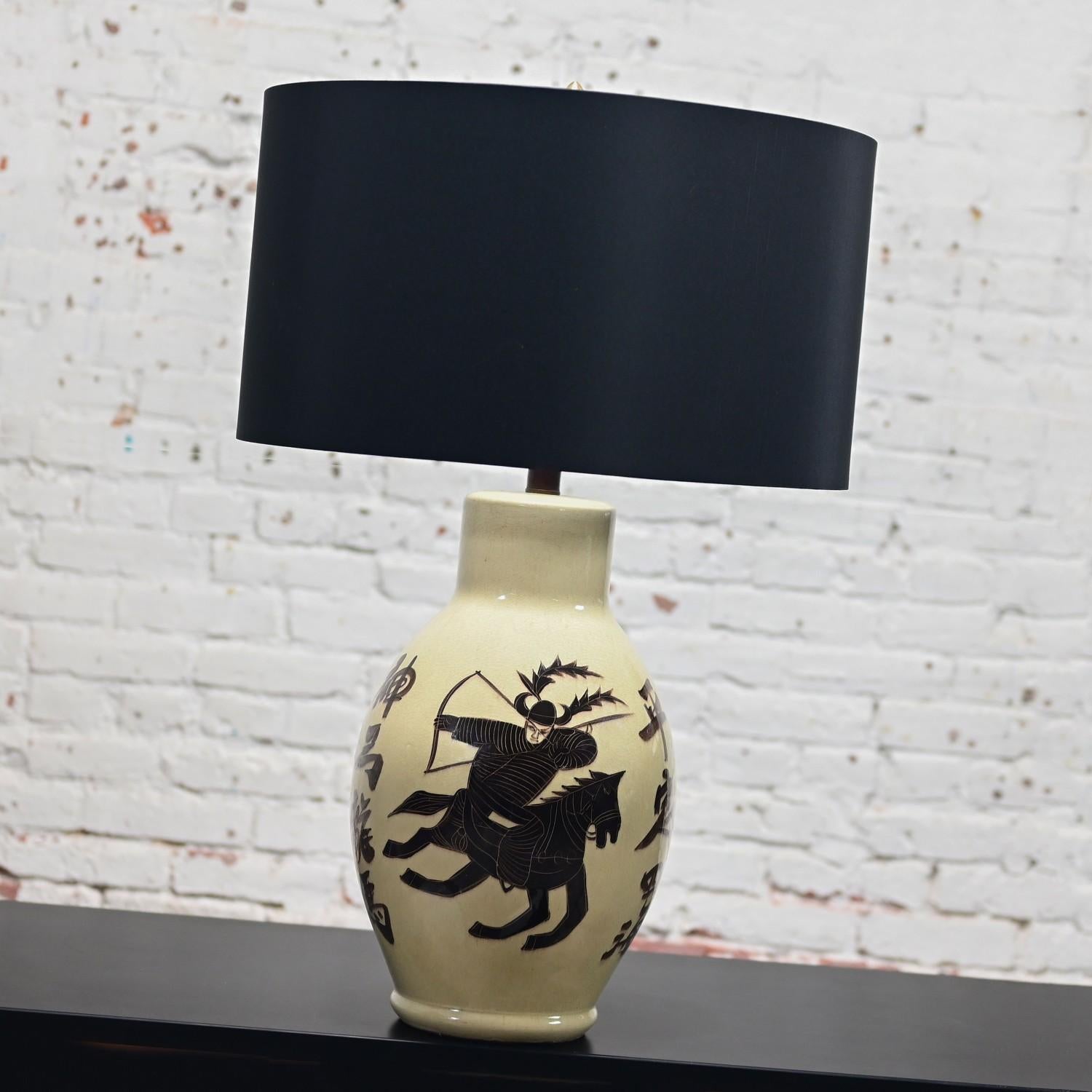 Marvelous vintage Asian Chinoiserie style large scale ceramic table lamp with a creamy off-white background & painted deep chocolate brown warrior on a horse and Asian writing with a glazed finish, new linen-like drum shade, 3-way switch, & a new