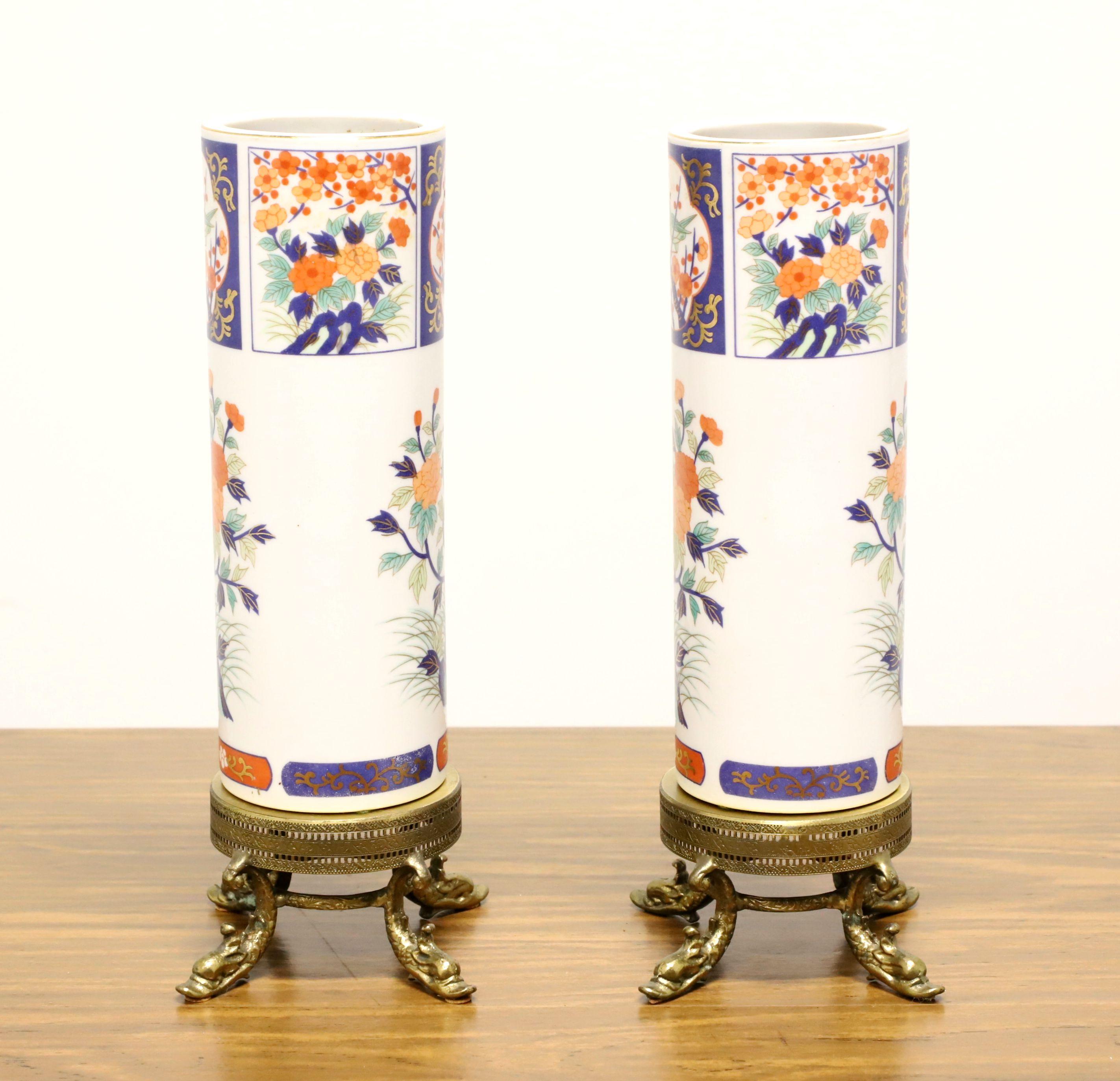 A pair of Asian inspired table vases on brass stands, unbranded. Hand painted porcelain with a Chinoiserie design of foliate & floral in shades of white, blue & salmon colors, and a cylindrical shape. Features the two porcelain vases on removable