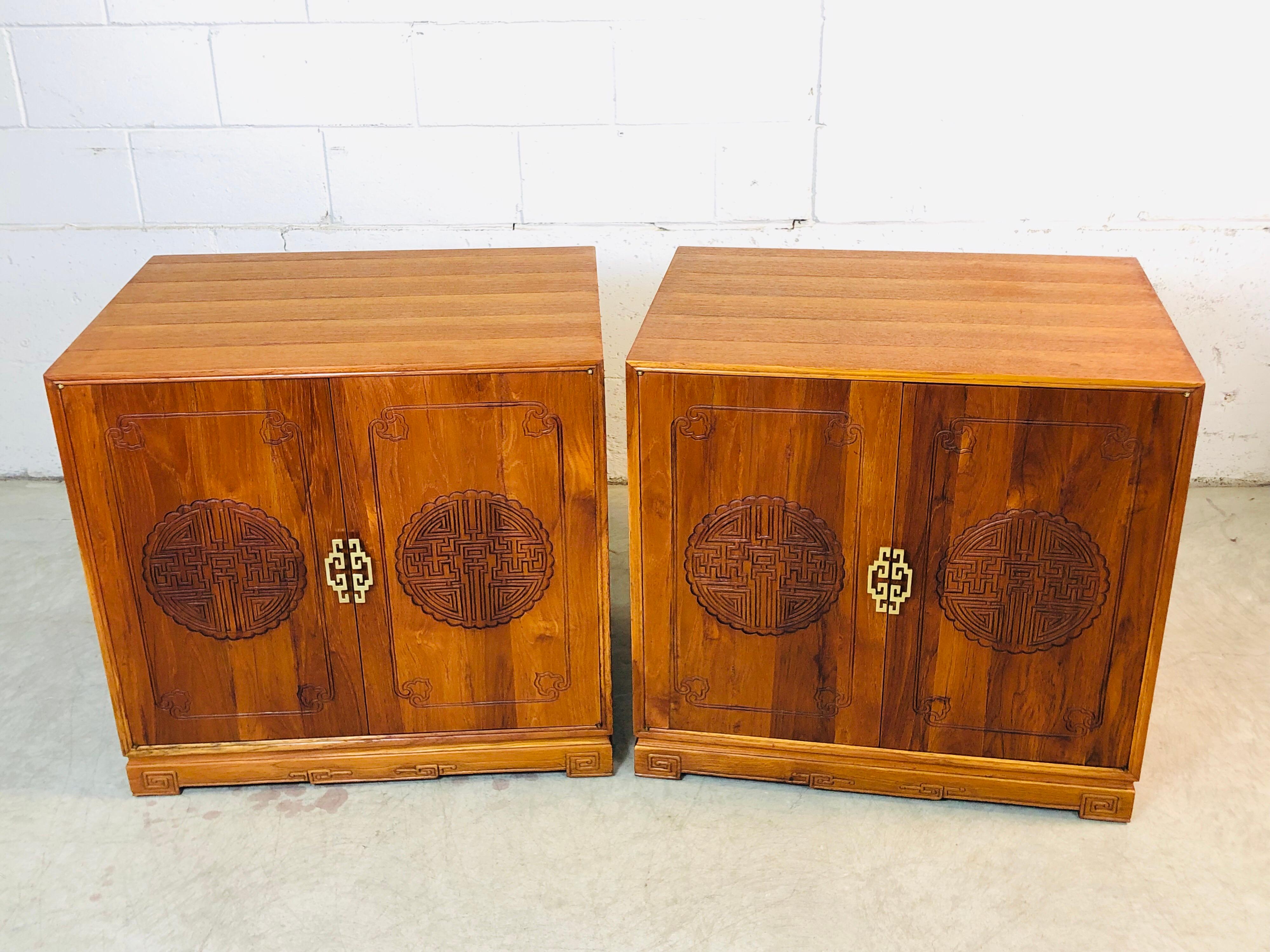 Vintage 1960s pair of Asian carved teak storage cabinets or side tables. The cabinets have polished brass pulls. One cabinet has shelves for storage and the other has drawers. They are in excellent refinished condition. No marks.