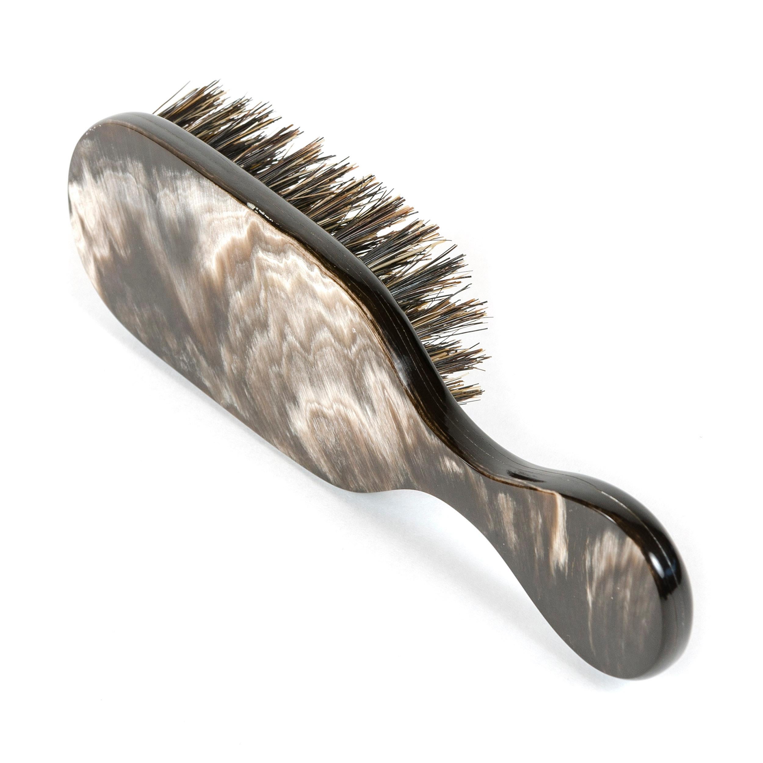 An elegant brush hand carved from cow horn with naturally occurring variations in color and pattern.