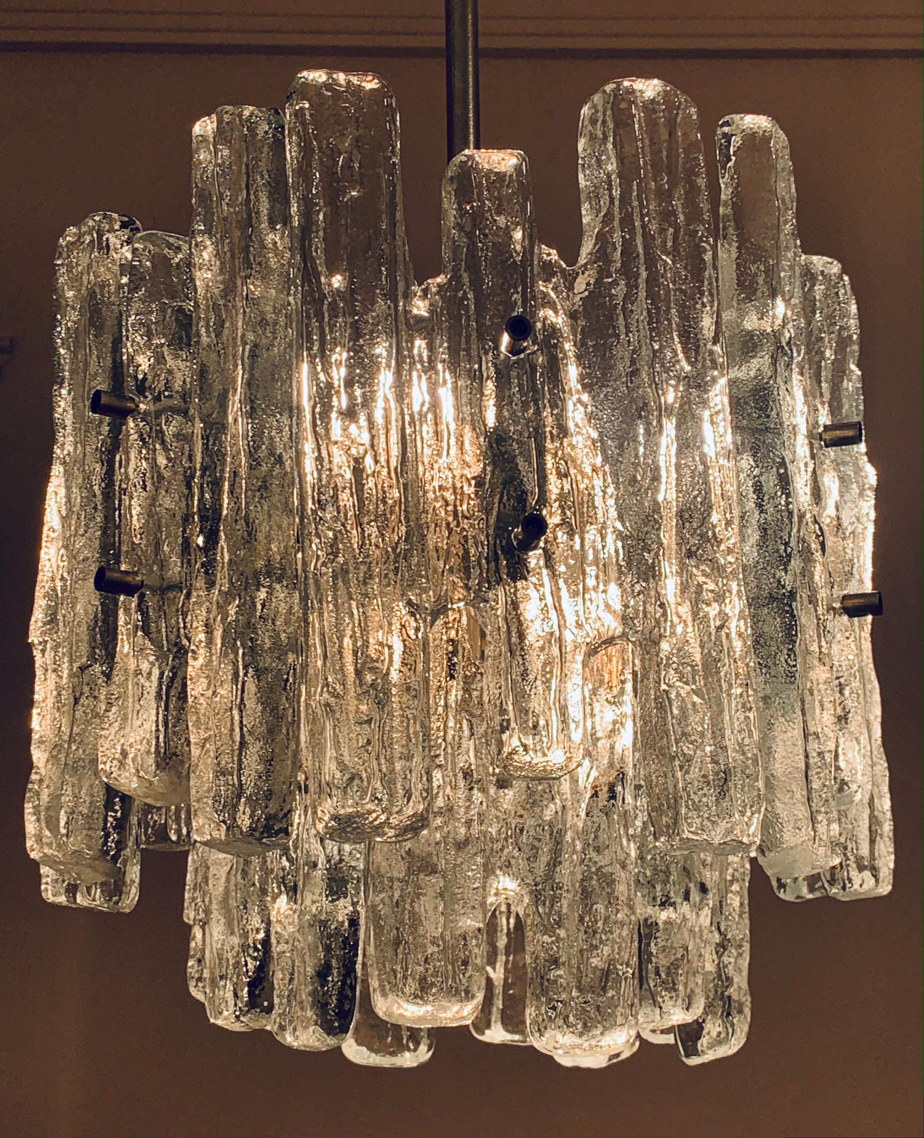 A striking and glamorous, two-tiered, iced glass, chandelier which was manufactured by Kalmar Lighting in Austria in the 1960s. Designed by J.T Kalmar. Each removable piece of heavy, block, iced glass is secured onto the chrome nickel metal frame
