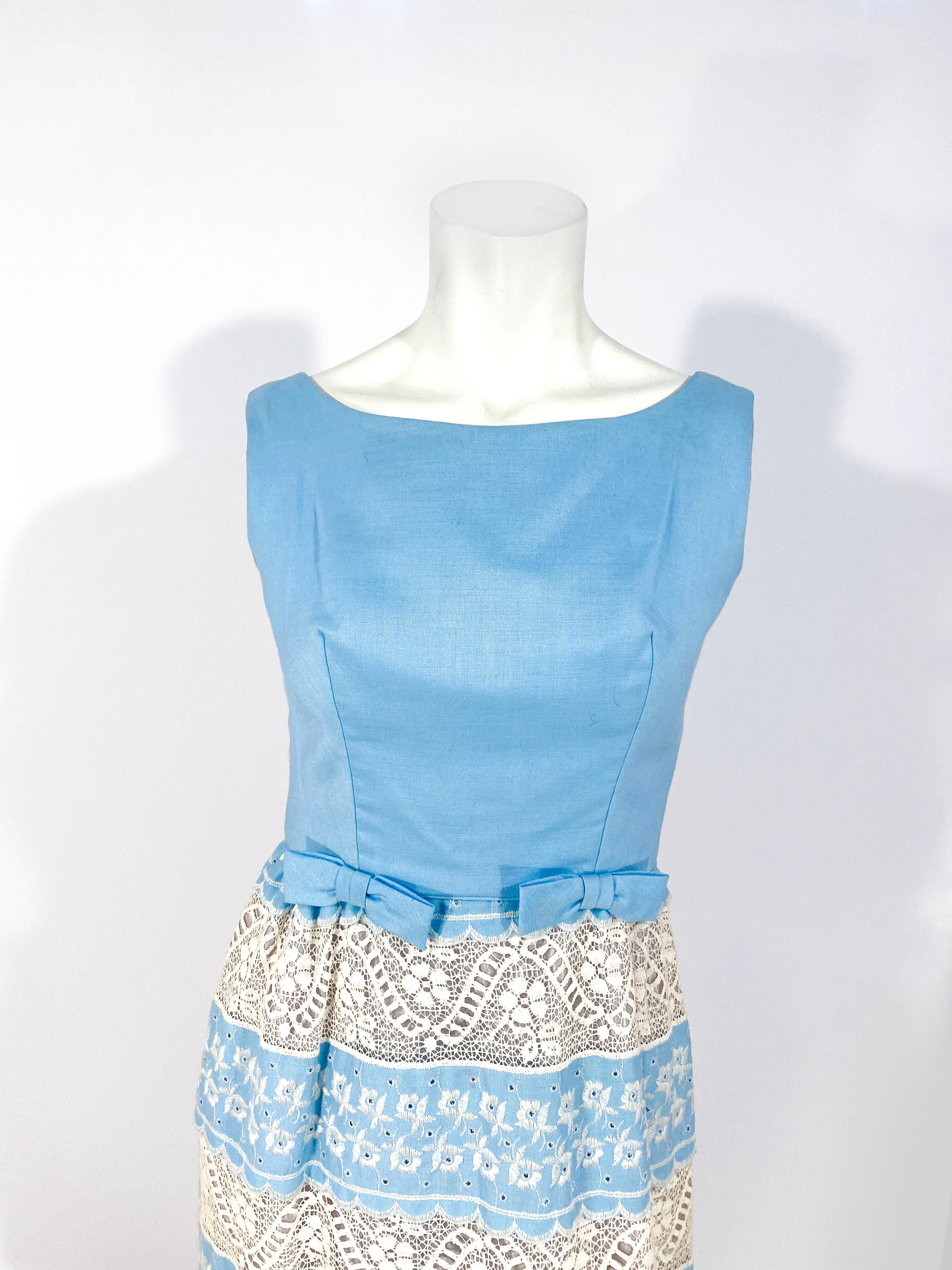1960s baby blue dress with ecru-colored embroidery and tiers of lace along the skirt. The hem is scalped and the waist is finished with tow bow accents along the piping. 