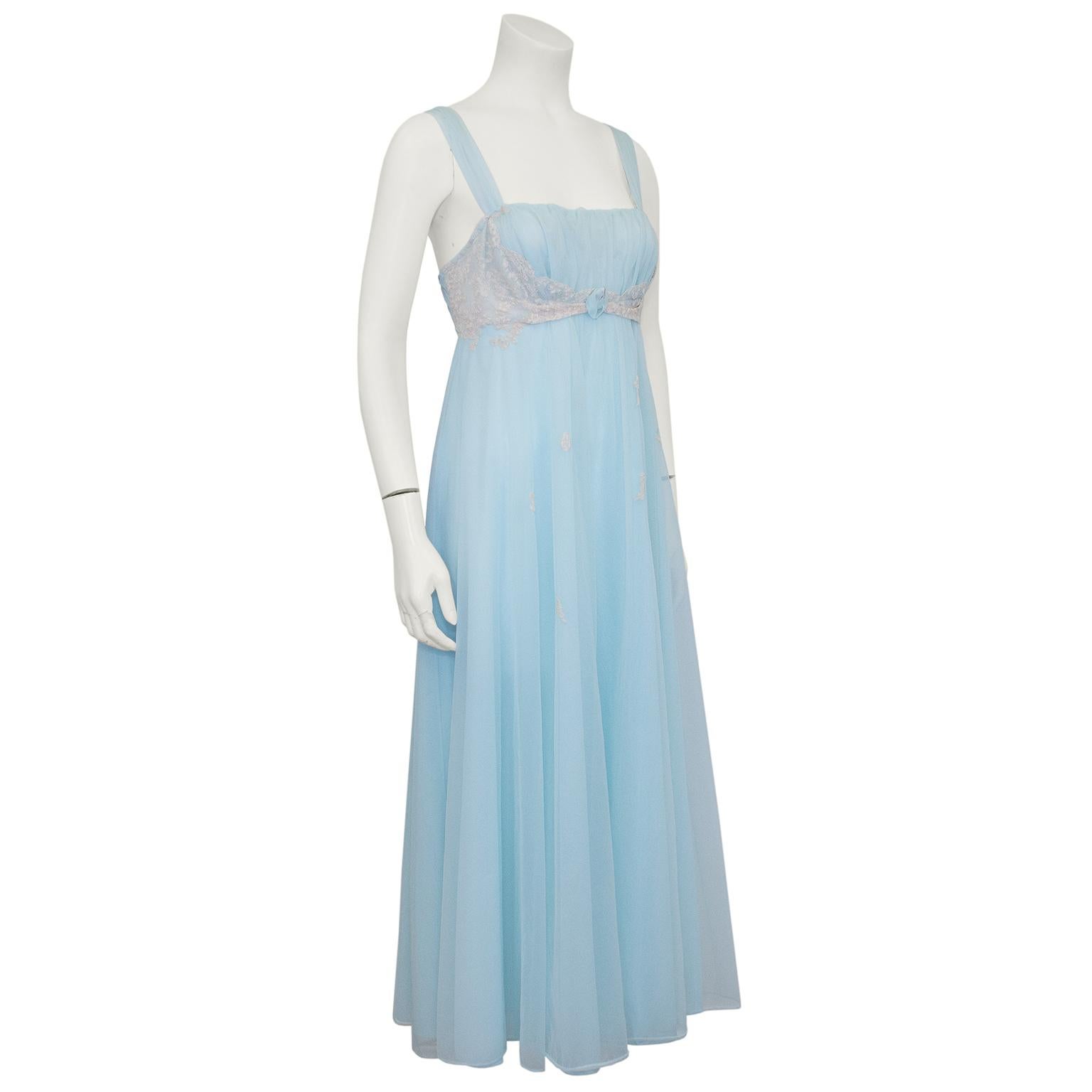 Beautiful 1960s baby blue nylon chiffon hostess gown featuring a gathered bust and empire waist with cream lace details and a baby blue rosette. Small lace details cascade down flowing floor length skirt. Back features same delicate lace details.