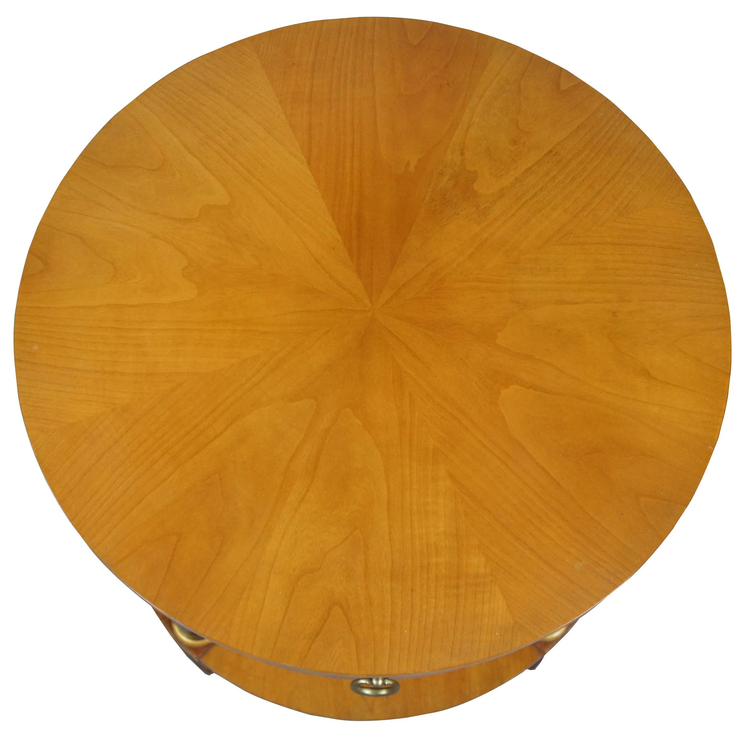 Baker Furniture French Empire fruitwood side table, circa 1960s. Feature a round two-tier design supported by ebonized columns with gold trim. Includes upper drawer with knocker pull.
 