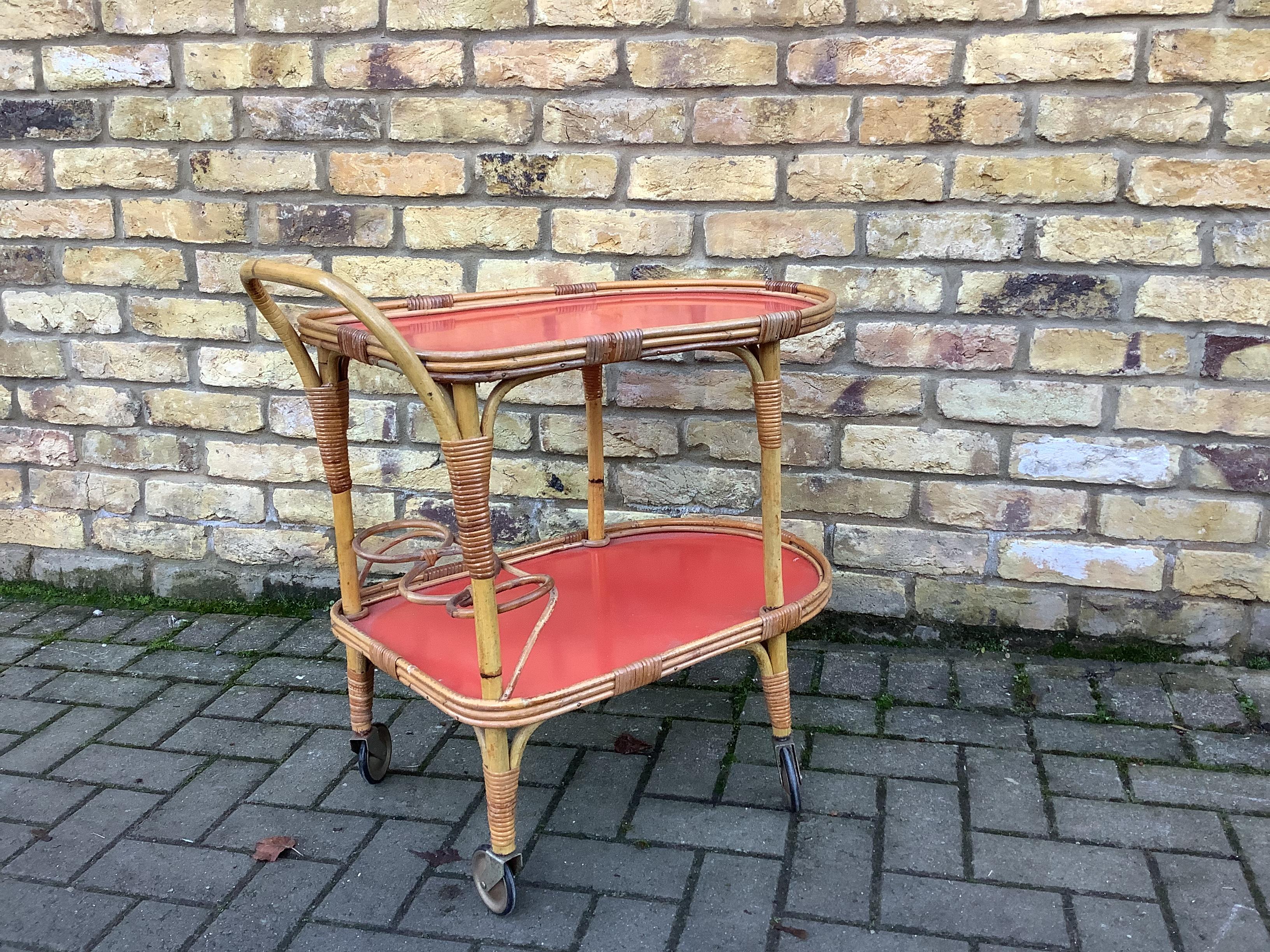 Bamboo drinks Trolley double shelving with red formica bases
Bottom shelve has 3 bottle holders woven out of the main body. Bar sits on 4 wheel castors.ideal drinks serving trolley.