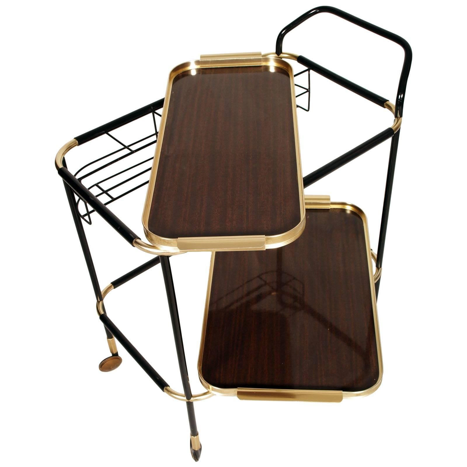 Elegant exceptional 1960s trolley bar cart, by MB Italia, in gilt brass encapsulated with black resin, with two removable trays in golden metal and double face mahogany formica.
Bottle holder in black lacquered metal
Exceptional conditions, like