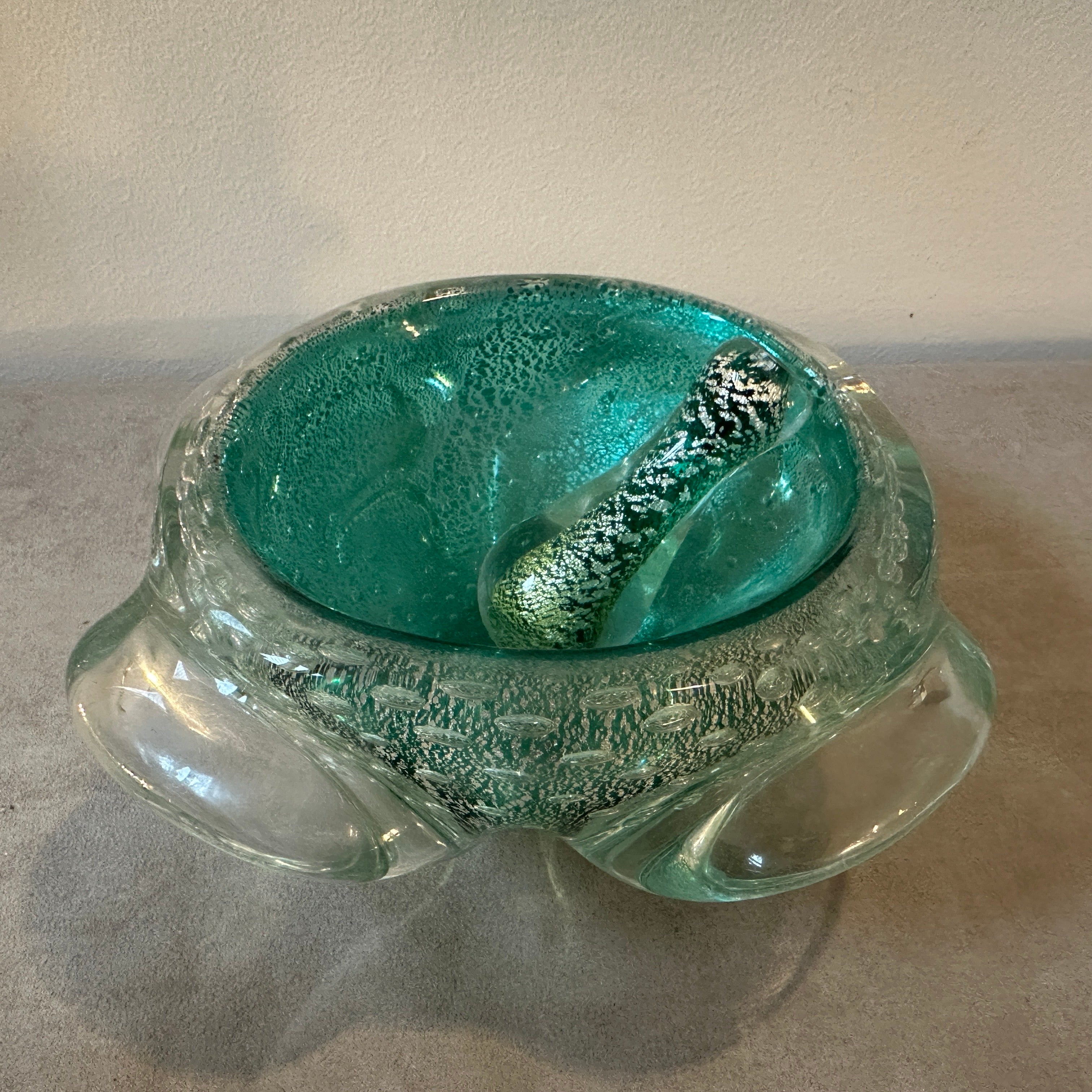 An heavy murano glass ashtray with original pestle designed and manufactured in Murano in the Sixties. green and gold bullicante murano glass it's in perfect conditions. Murano glass is a high-quality glass renowned for its clarity, color, and