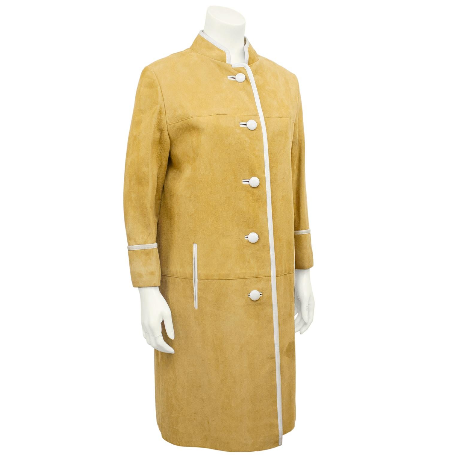 Mod 1960s coat from Saks Fifth Avenue. Natural tan suede color  with cream kidskin trim and buttons. Mandarin collar and vertical slit pockets. Cream, tan and black wool windowpane plaid lining adds warmth and a level of mod chic. Excellent vintage