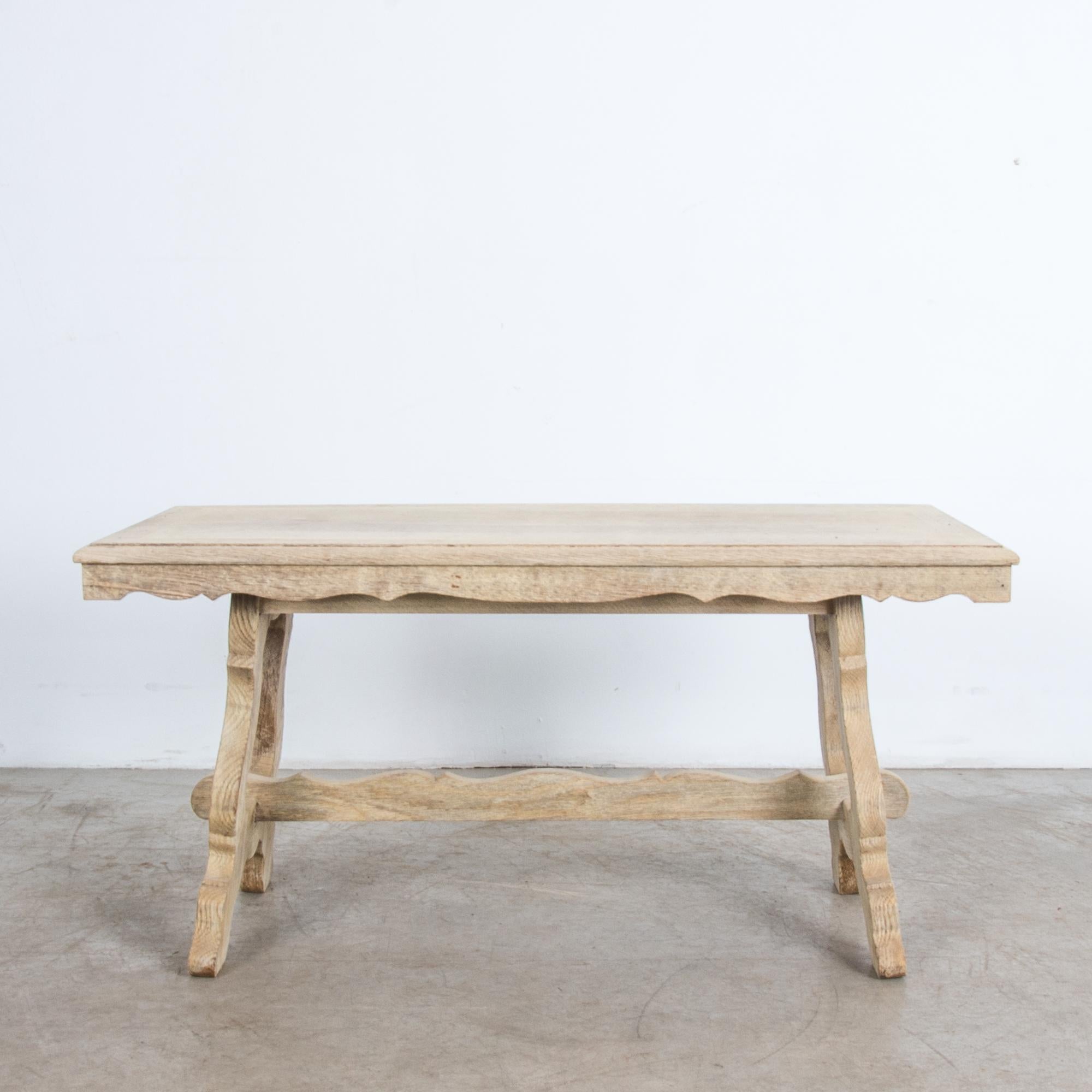 A typical mid-20th century Belgian style re-imagines traditional shapes in thick slabs of oak. Rustic simplified, with an elegant note of classical style. Thick legs support the tabletop from either side, supported by a trestle post. With clear oil