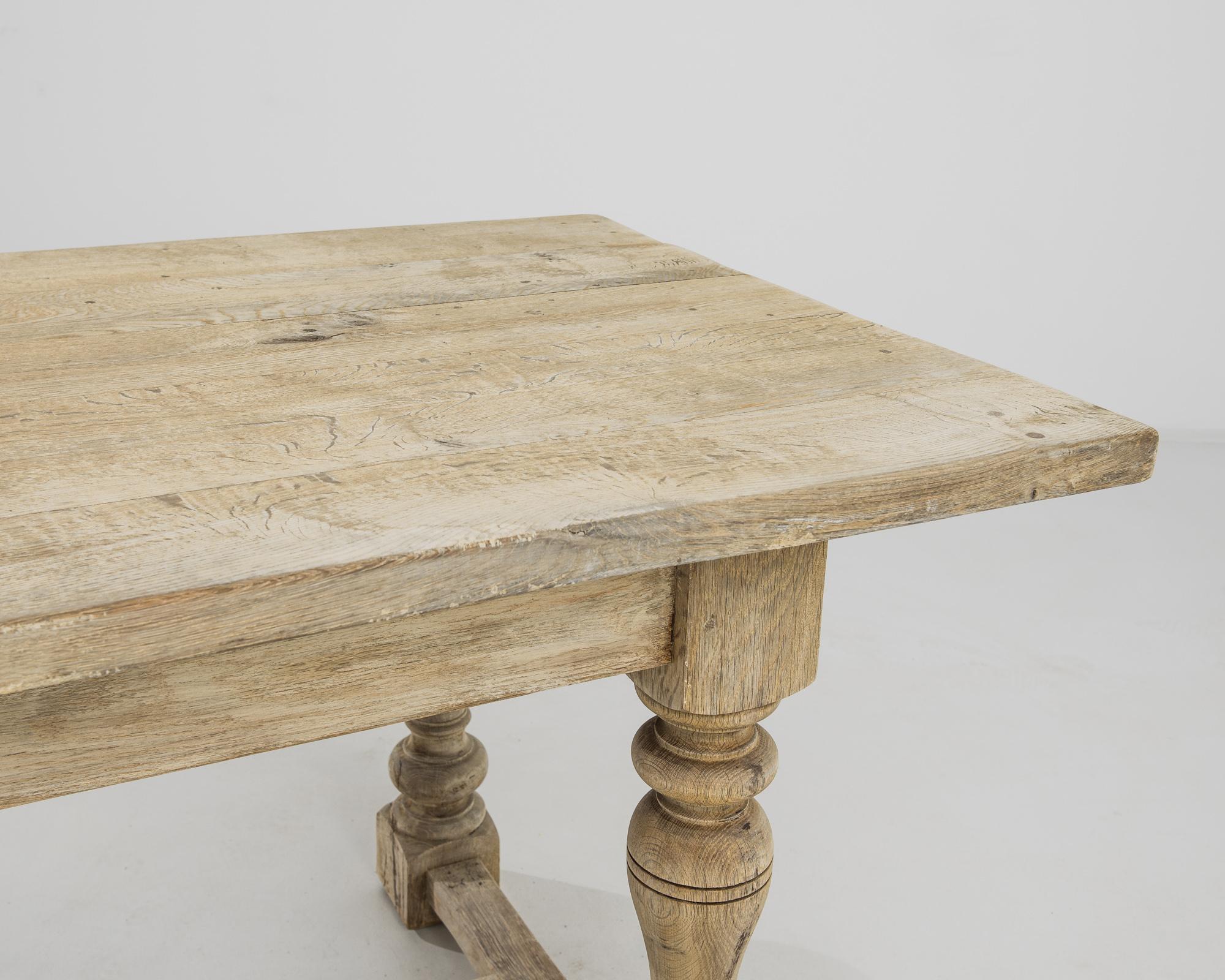 A bleached oak dining table from Belgium, produced circa 1960. Sporting a five and a half foot wide top, this sturdy table can comfortably sit a party of four to six. Stunning craftsmanship still shines through even after decades of life laden with