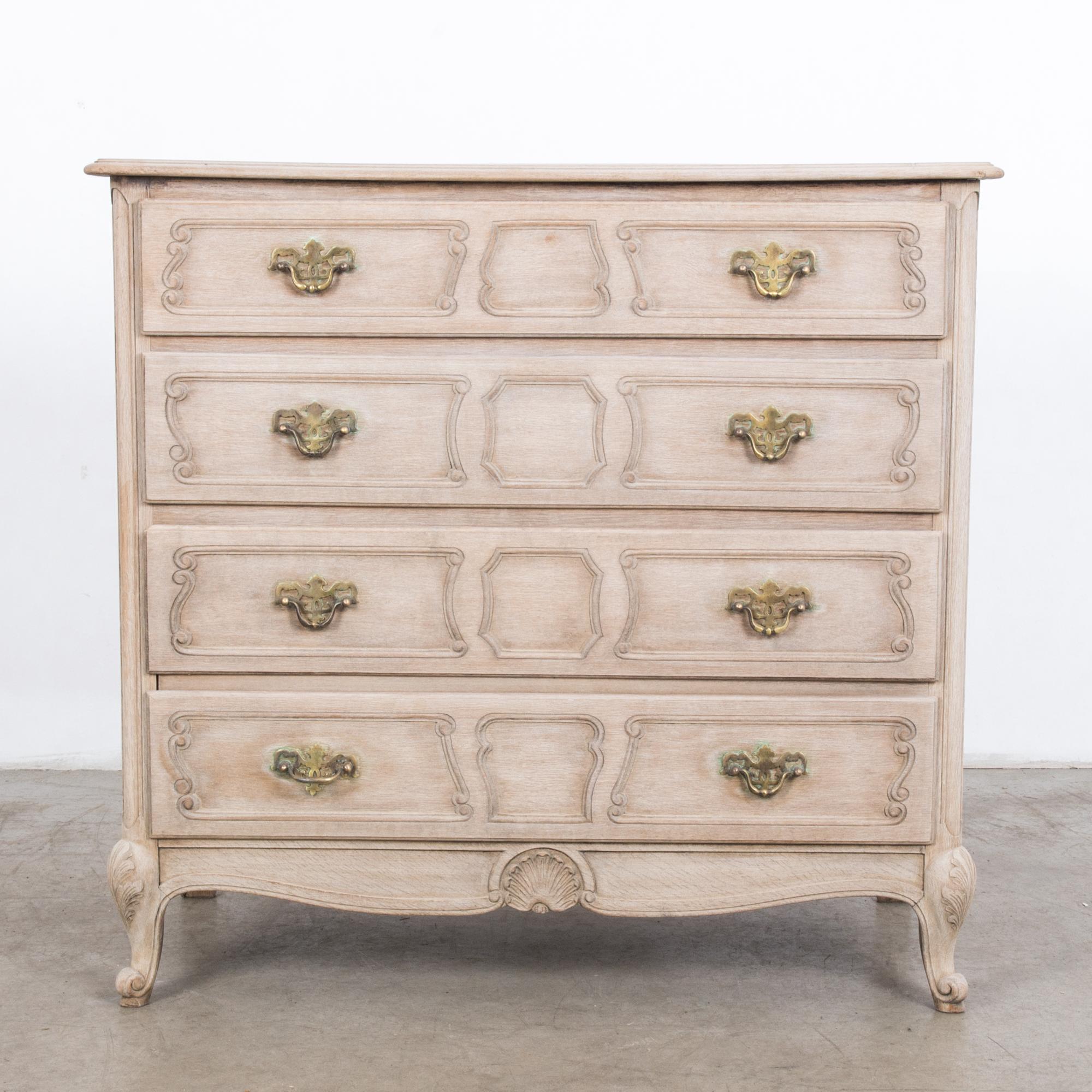 From Belgium circa 1960, a four-drawer chest in raw oak finish. The simple shape and subtle ornament is accentuated by cast bronze handles. Produced with traditional techniques and seasoned by time, this charming chest is a practical and stylish