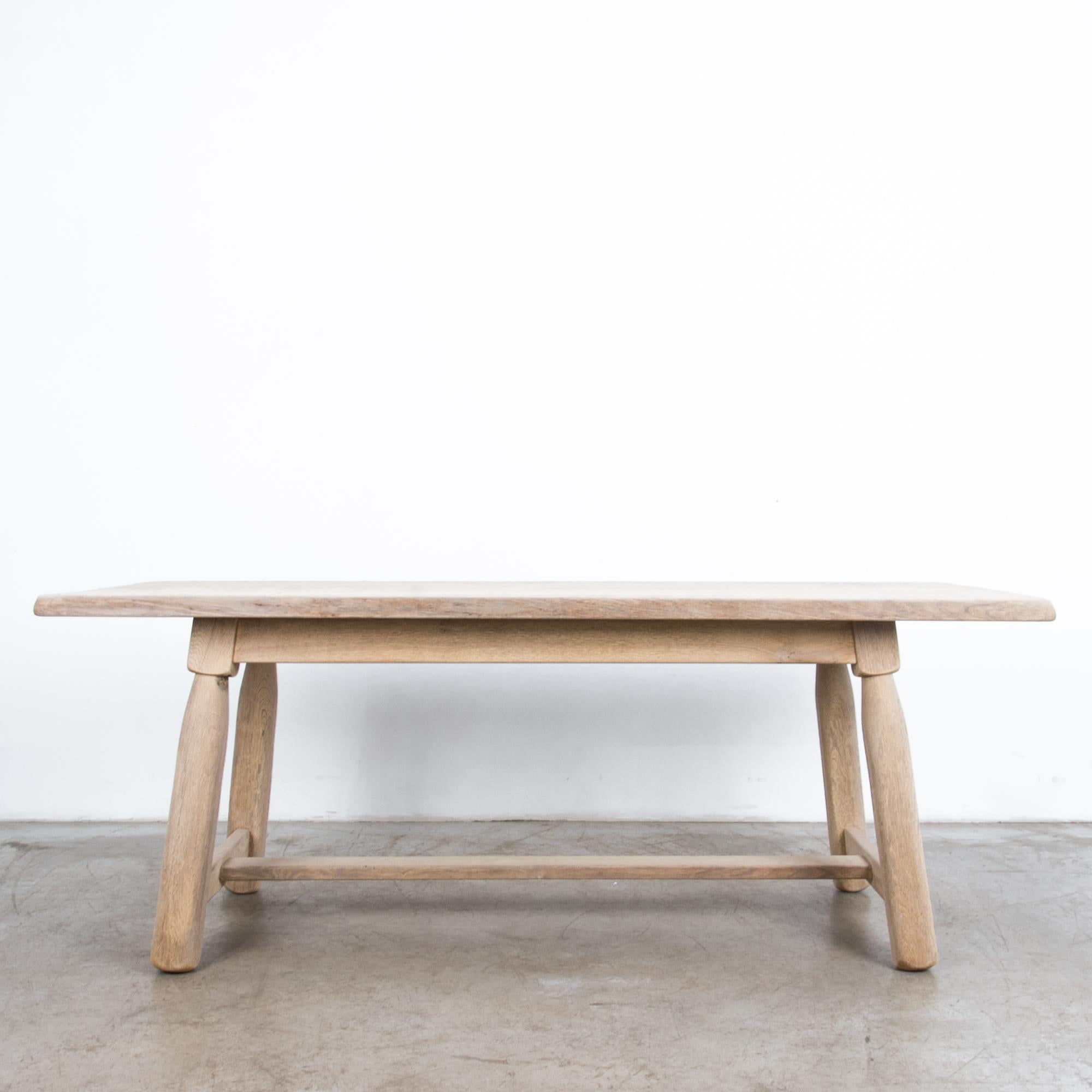 Rustic and simple Belgian style farmhouse table from the 1950s in bleached oak, features distinct rounded legs and trestle brace. Simple wooden forms recall the countryside ideal, following the lineage of European craftsmanship, with modernist