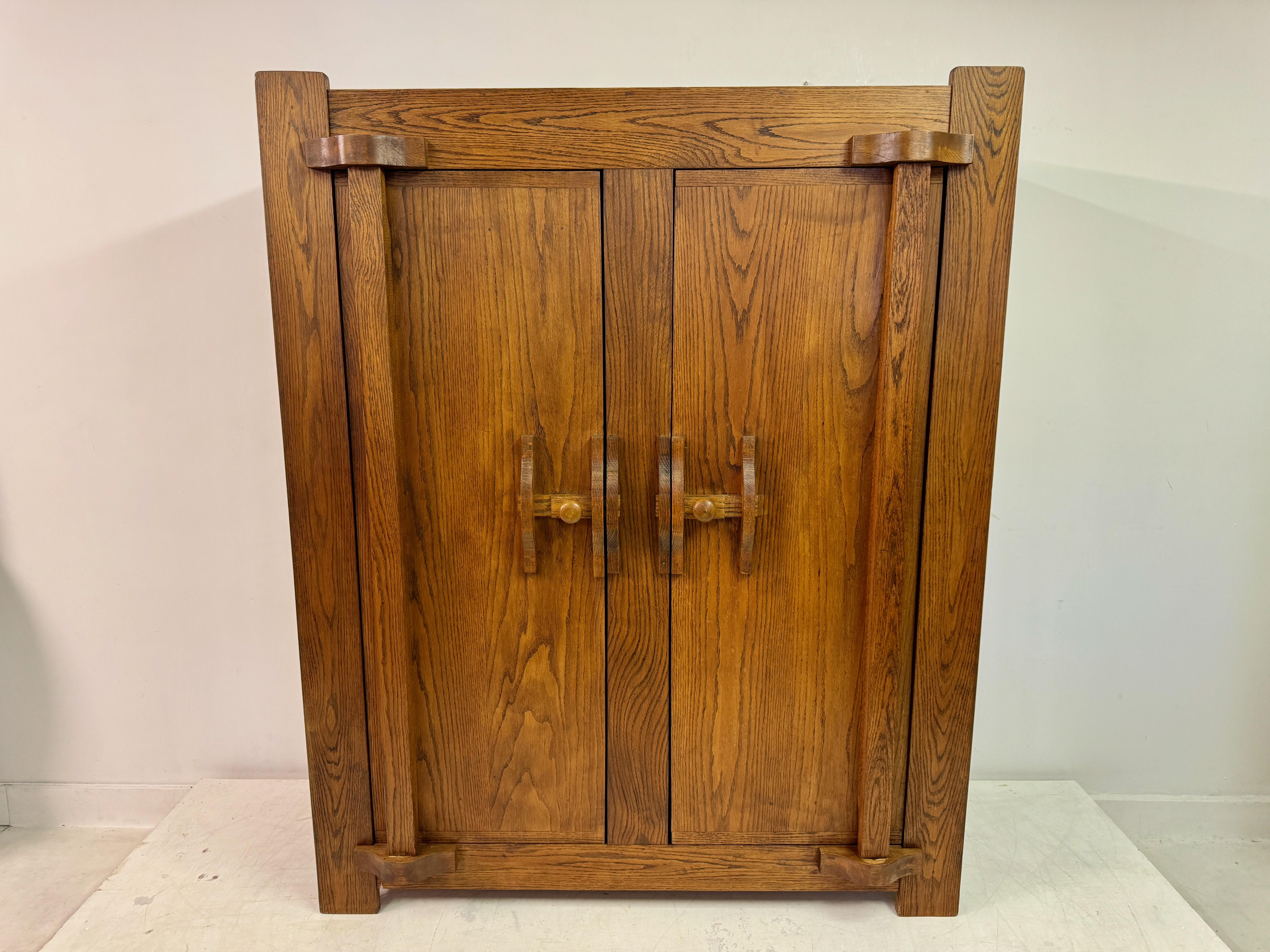 Vintage Belgian cupboard or wardrobe from the 1960s. The piece is crafted from rich, warm-toned oak, showcasing a beautiful natural grain pattern that adds to its character and charm. The design features clean, straight lines typical of mid-century