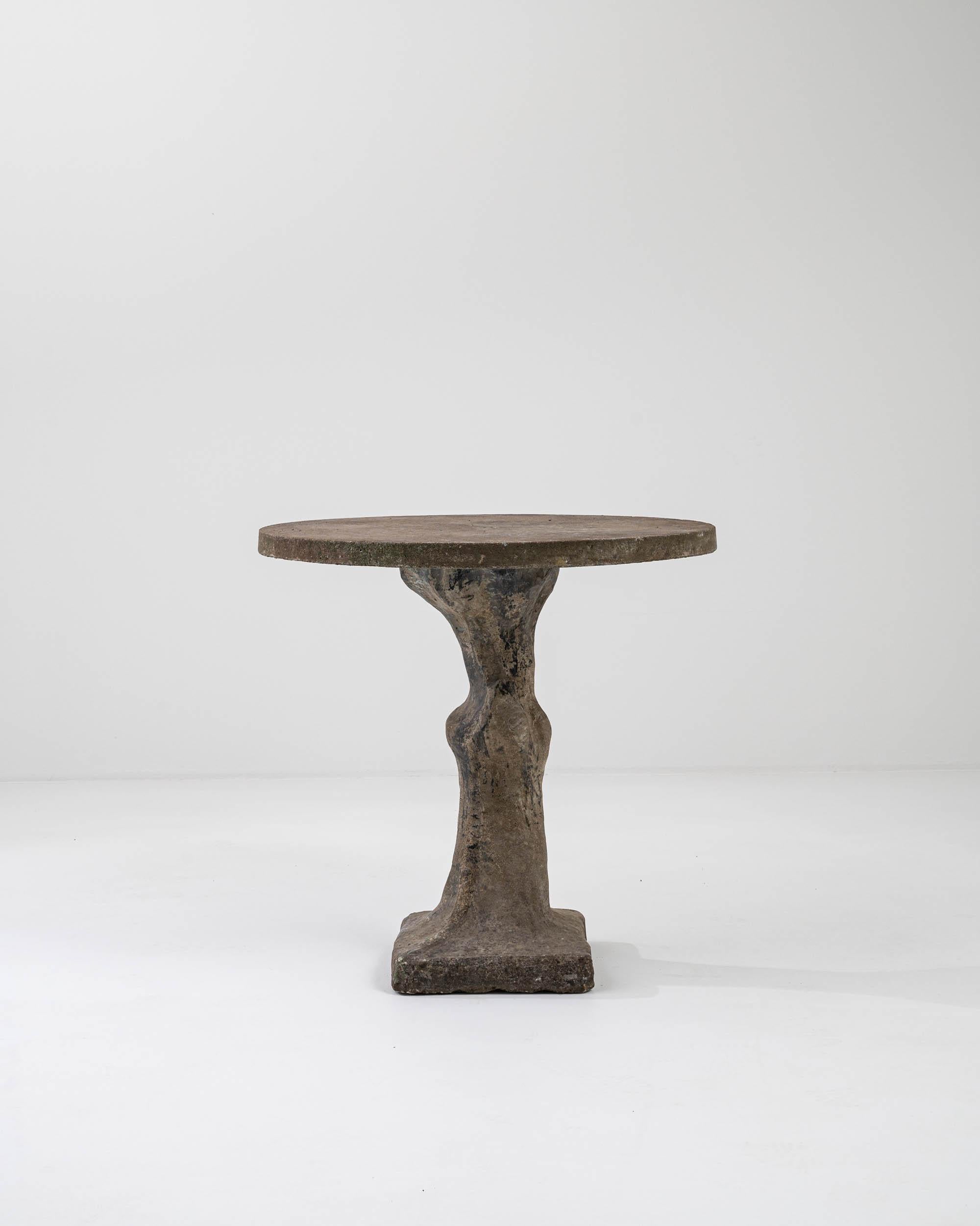 The compelling form of this vintage table — at once abstract and organic — gives it a unique, sculptural appeal. Made in Belgium in the 1960s, a circular tabletop rests atop an asymmetric base. The knotty yet elegant form of the central pedestal is