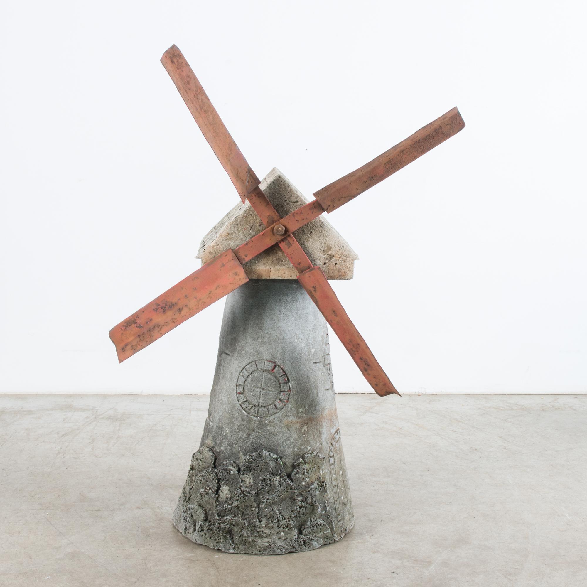 This concrete windmill ornament was made in Belgium, circa 1960. It is a delightfully charming piece, with its handcrafted quality and carvings of tiles on the roof and a door at the bottom. Red metal pieces with a weathered patina are assembled in