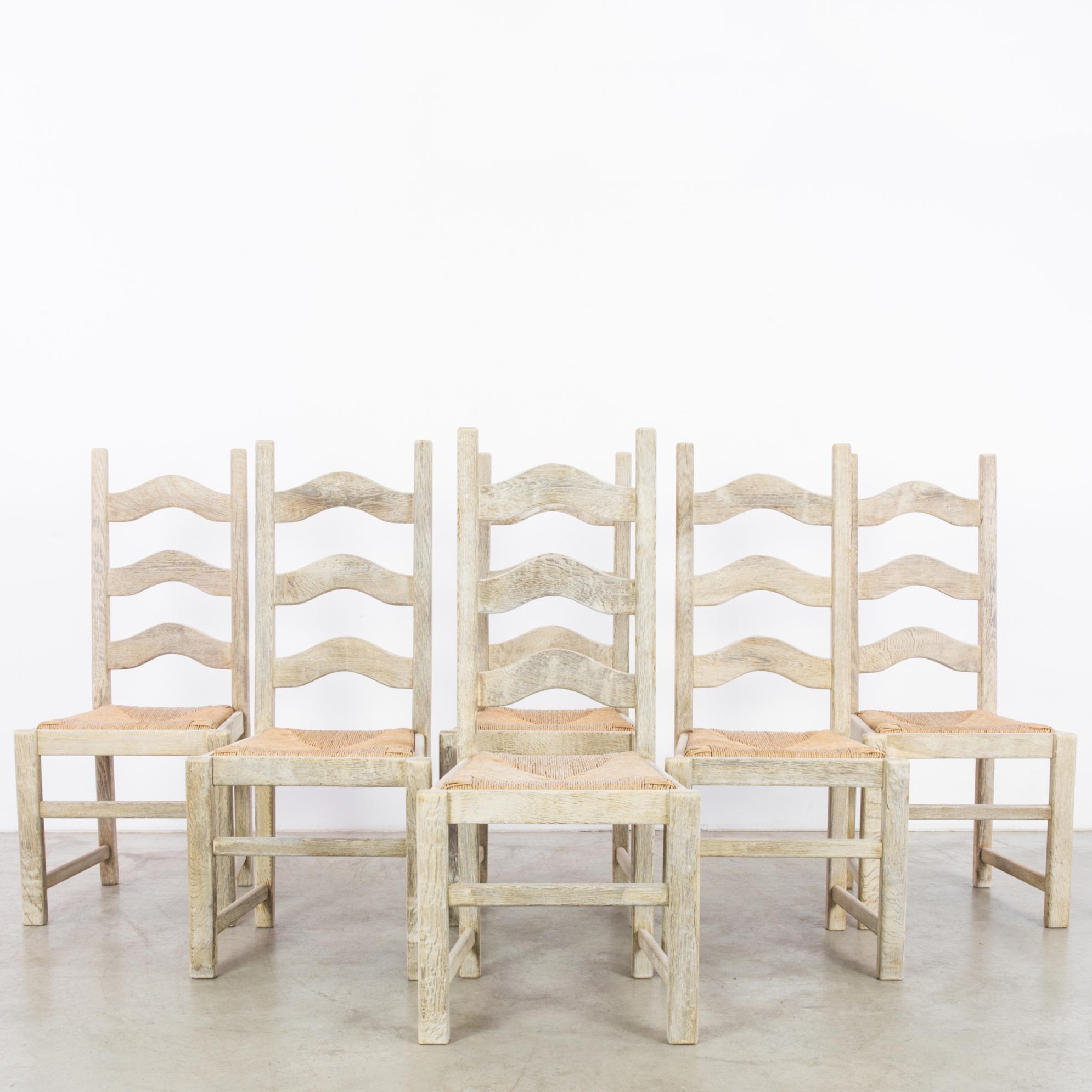 A set of six wooden dining chairs with woven seats from Belgium, produced circa 1958. Featuring tall ladder style back rests, straight struts, and a refurbished weave, these are a set of beautifully crafted rustic chairs. The rhomboid shape of the
