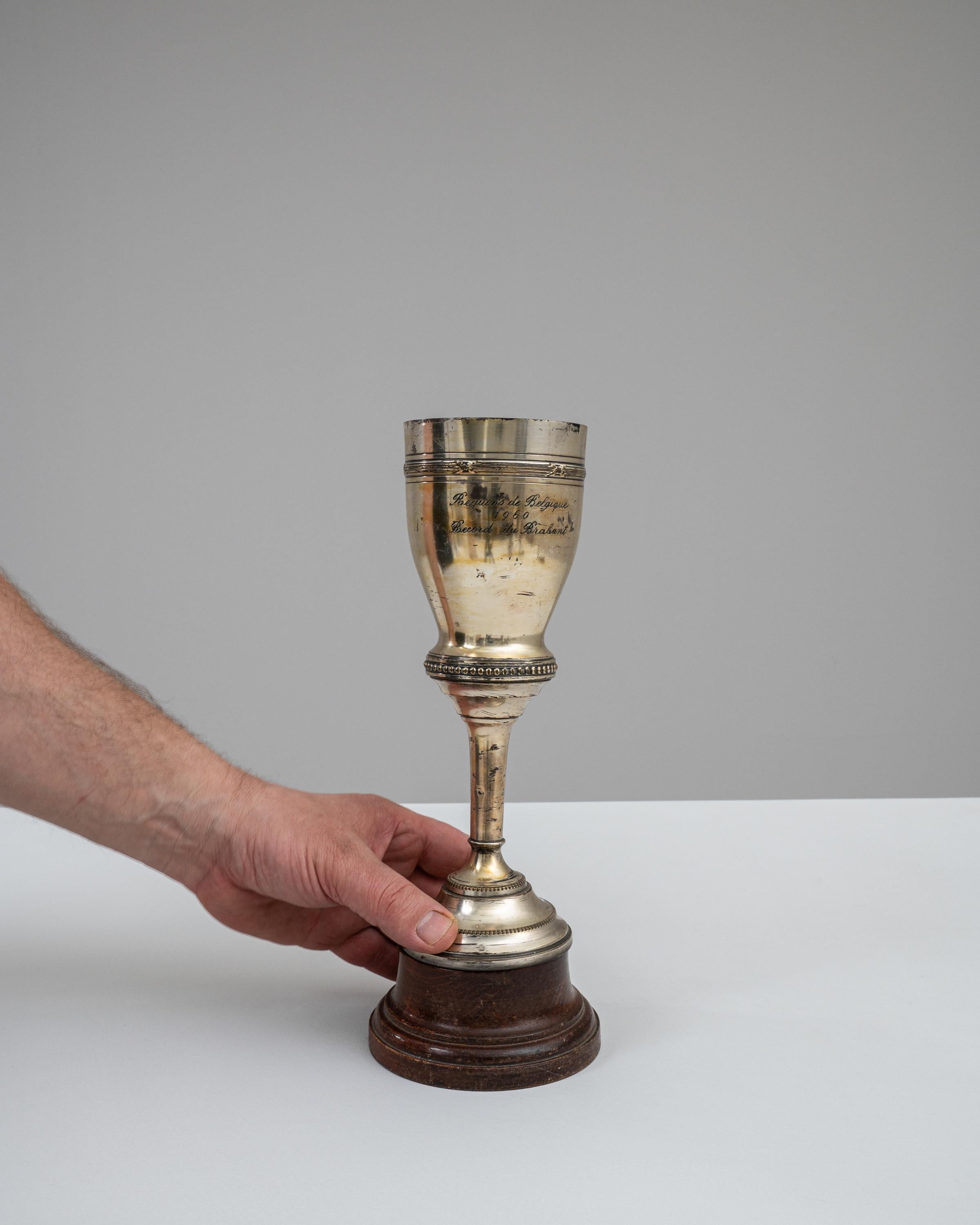 This 1960s Belgian Metal Goblet is a prestigious artifact, reflecting the competitive spirit of the era with its tarnished yet imposing presence. Awarded for a record-setting achievement as inscribed with 