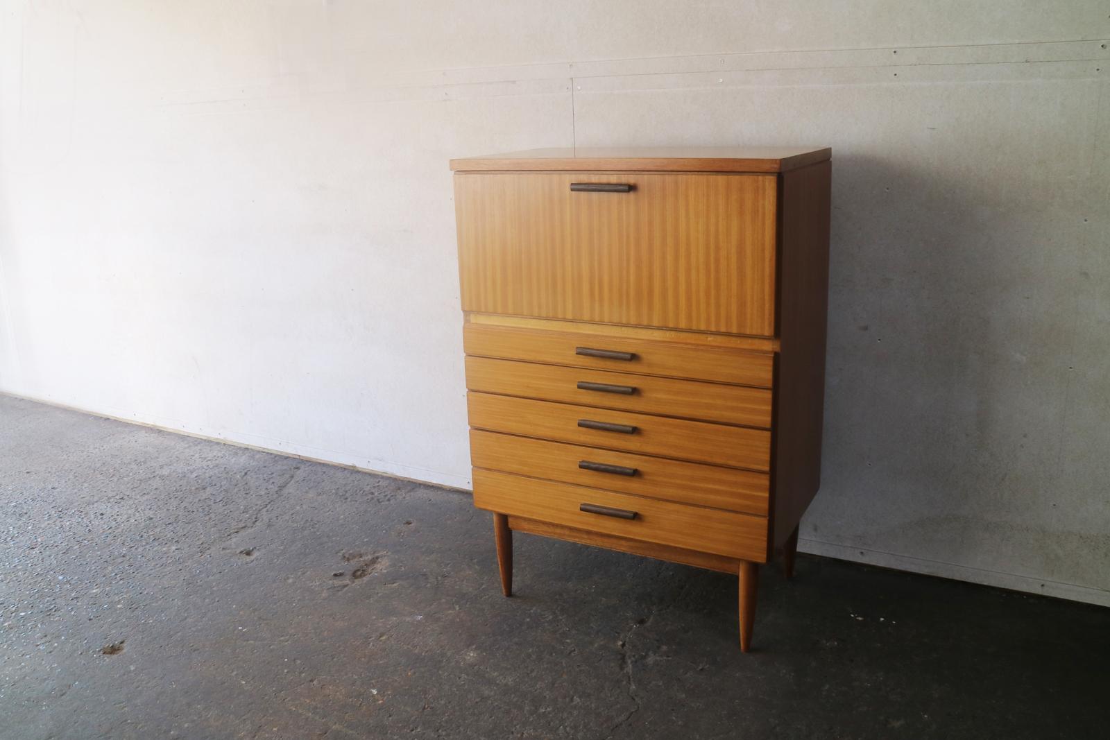 A smart midcentury multi-purpose teak bureau made in Belgium in the 1960s. At the top is a flap opening cupboard, and below are four drawers, the lowest one cleverly looking like two drawers but is in fact one.

 