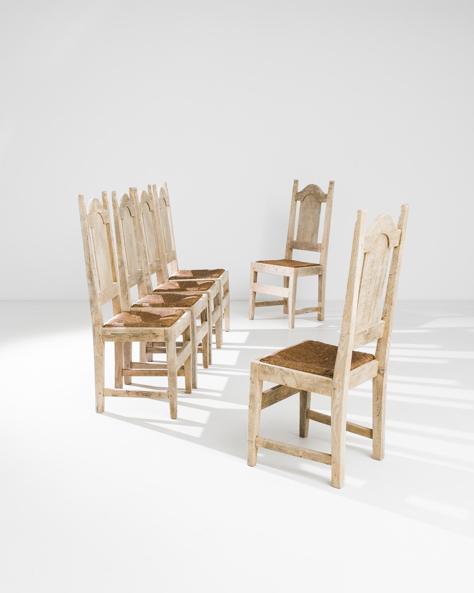 A set of six wooden dining chairs with wicker seats from Belgium, produced circa 1960. Like seats built for the great hall of an old manor, these rustic country seats are made for enjoying the finer things in life.