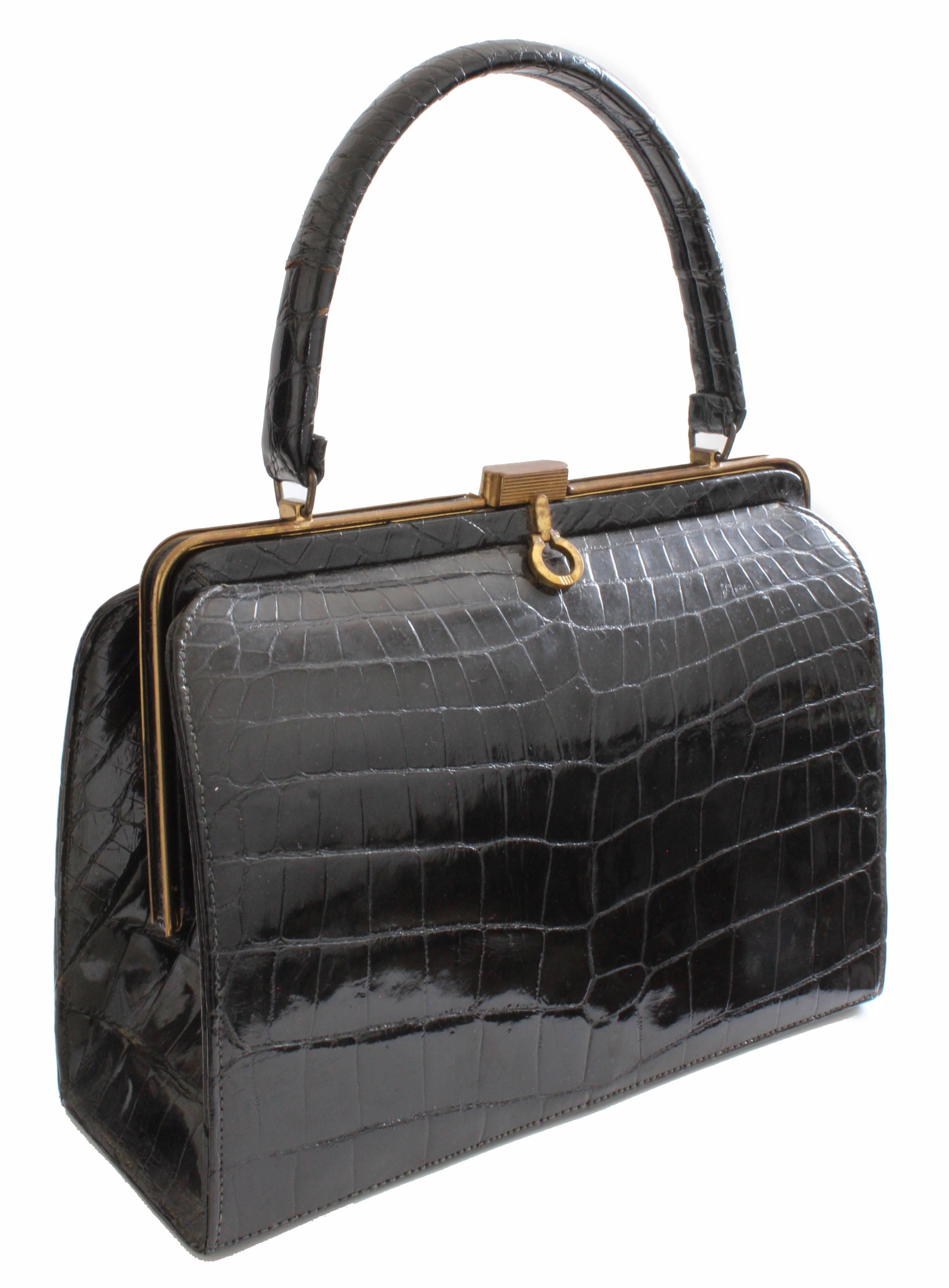 This vintage bag was made by Bellestone, most likely in the early 1960s.  Made from glossy black crocodile skins, it fastens with a gold metal clasp.  Lined in beige leatherette fabric, it features one zipper pocket and two flat open pockets.  Note
