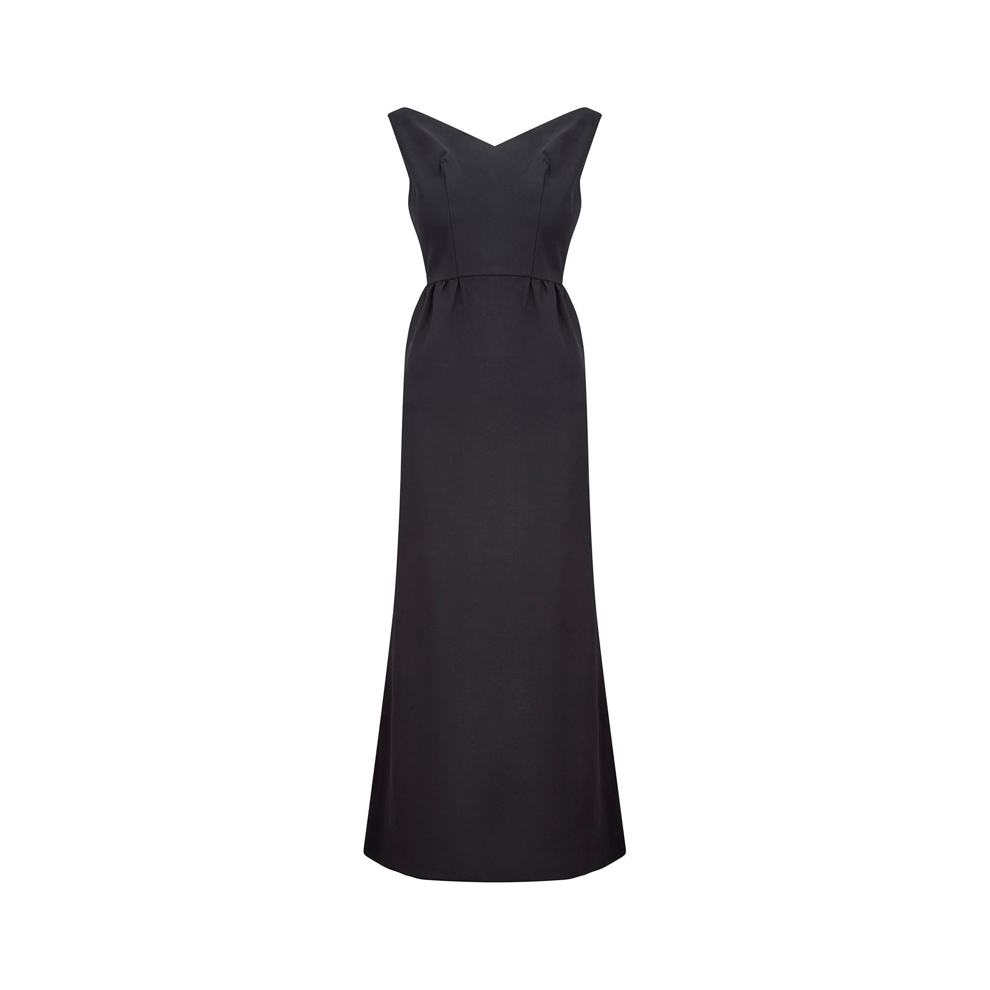 Made in the 1960s, this classic, sleeveless black crepe dress is in excellent vintage condition. A V-shaped, wide neckline reveals the decolletage. Delicate pleating at the rear and flared, fishtail tailoring to the skirt add interesting detail to