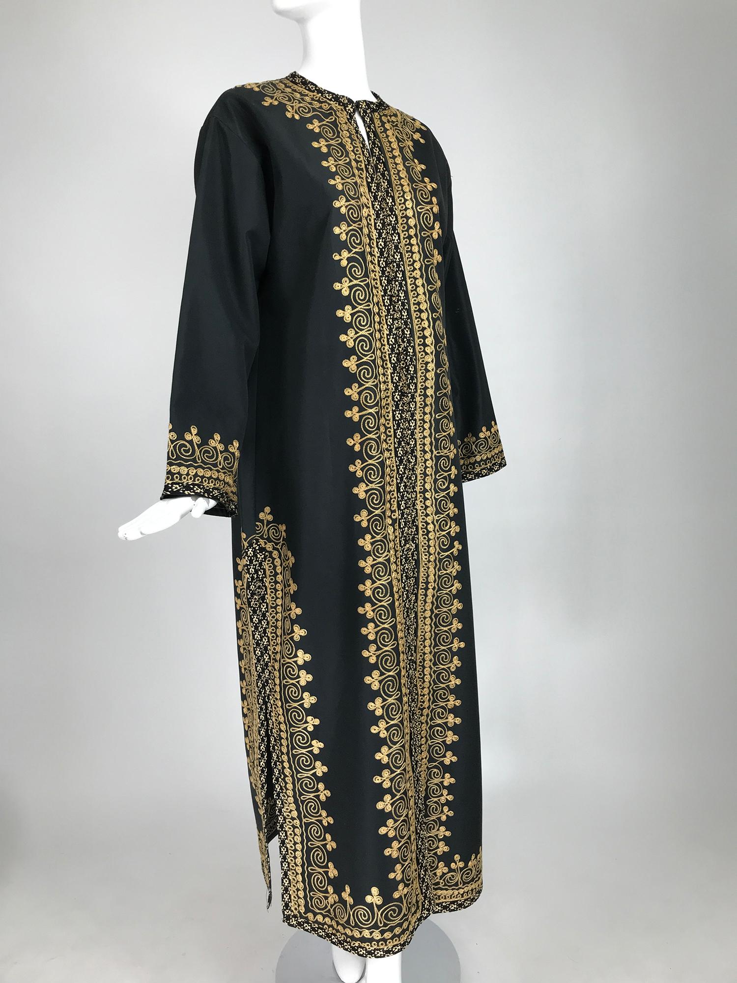 1960s black embroidered caftan with black & tan woven raffia trim. An unusual caftan with a bold design woven of black & tan raffia. Long sleeve caftan has a hidden zipper closure at the front. A line full shape. Fits size medium. 
     In excellent