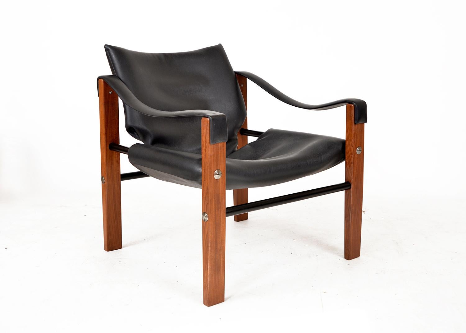 Stunning Safari lounge chair, “Chelsea” model, designed by Maurice Burke in the 1960s for Arkana. The heavy black faux leather is soft and in great condition, accented with over-sized stainless steel rivets on a solid African teak frame and steel