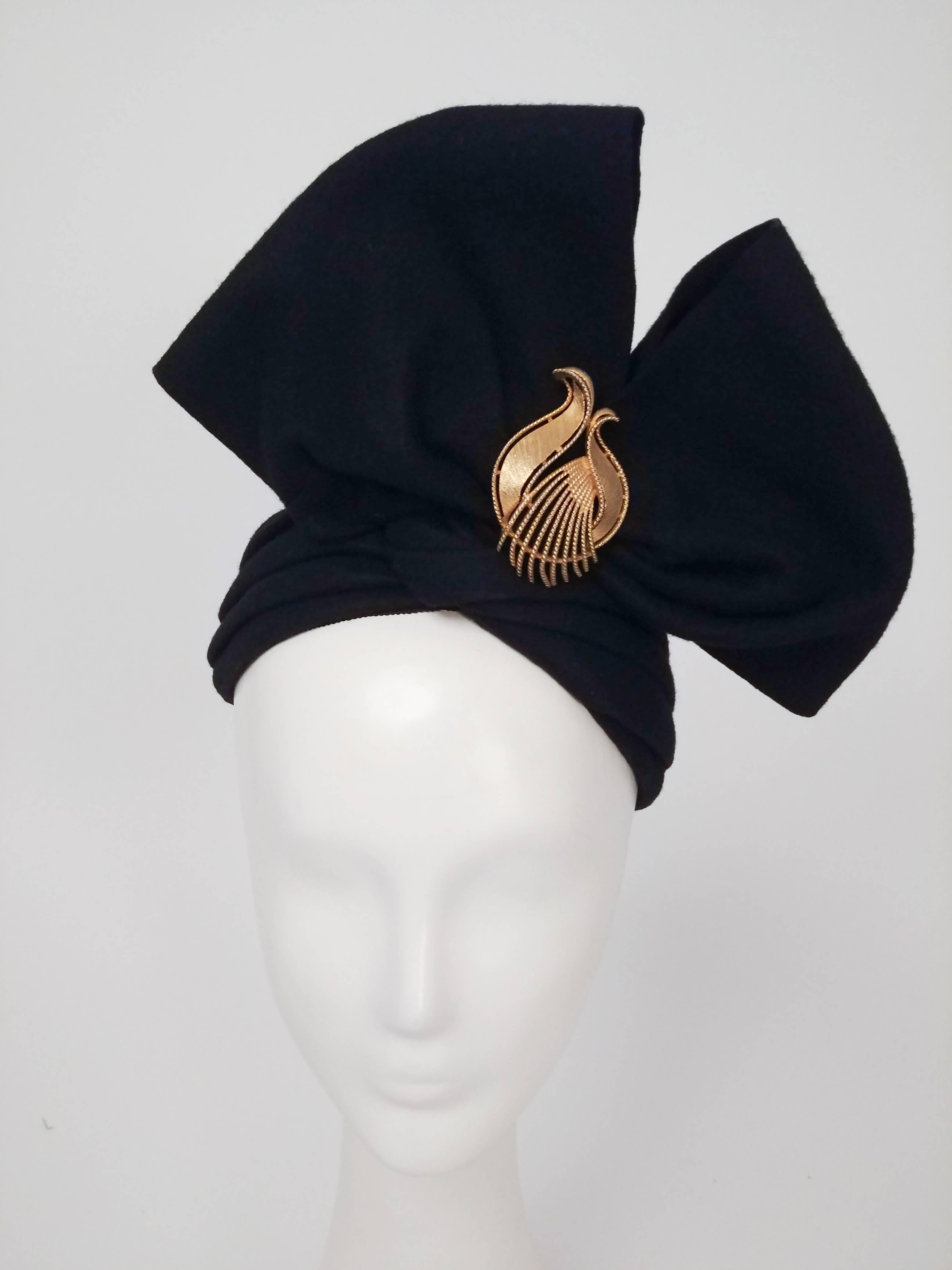 1960s Black Felt Structured Bow Hat. Artistic turban-like hat perches towards back of head with large structured bow, finished with gold-tone decorative brooch. 