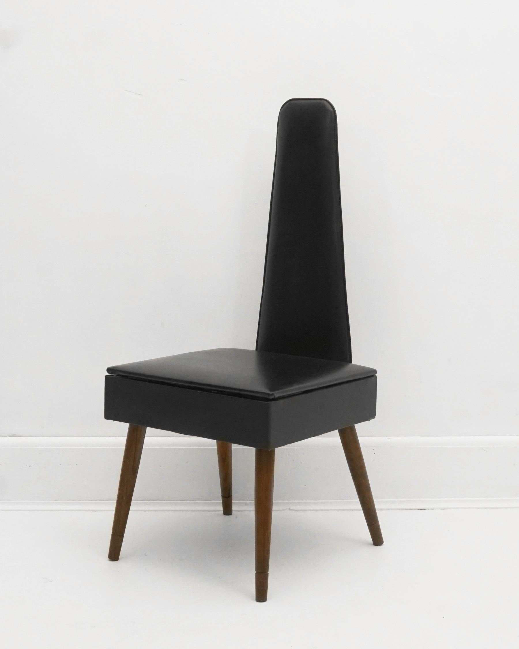 1960s black valet chair with seat storage. Vinyl is almost in perfect condition. The vinyl covered hinged seat opens to reveal a storage compartment. Wooden tapered legs. Great condition with very minor wear due to age and use. Originally designed