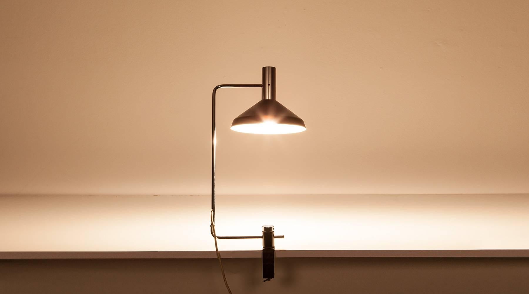 The double pivoting desk lamp designed by Rico Baltensweiler made for clamping to a table can be posed in various positions and comes in lacquered aluminum and metal, the adjustable pole is chromium plated steel. Manufactured by Baltensweiler AG. We