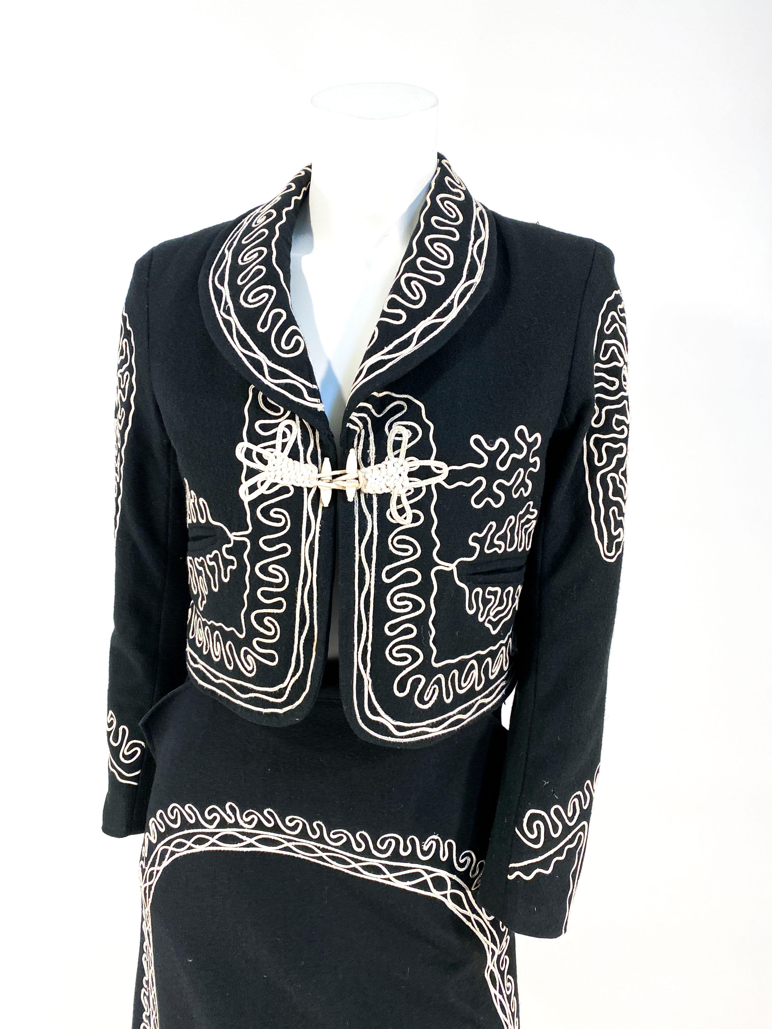 1960s black wool mariachi charro suit with white soutache designs through the jacket and skirt, two hand pockets at the waist of the skirt, full lining and handmade frog closure. 