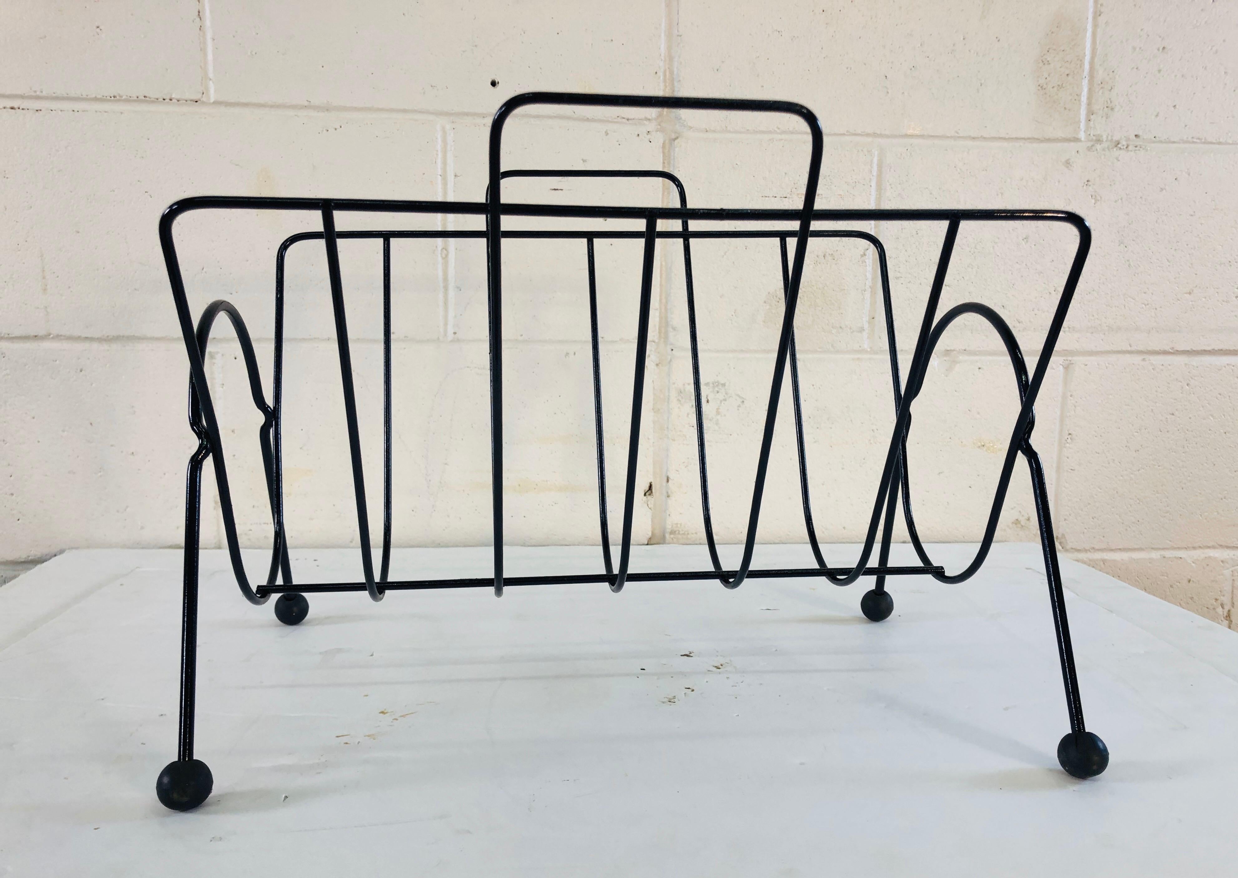 1960s black metal magazine rack with black runner ball feet. Newly restored and refinished.