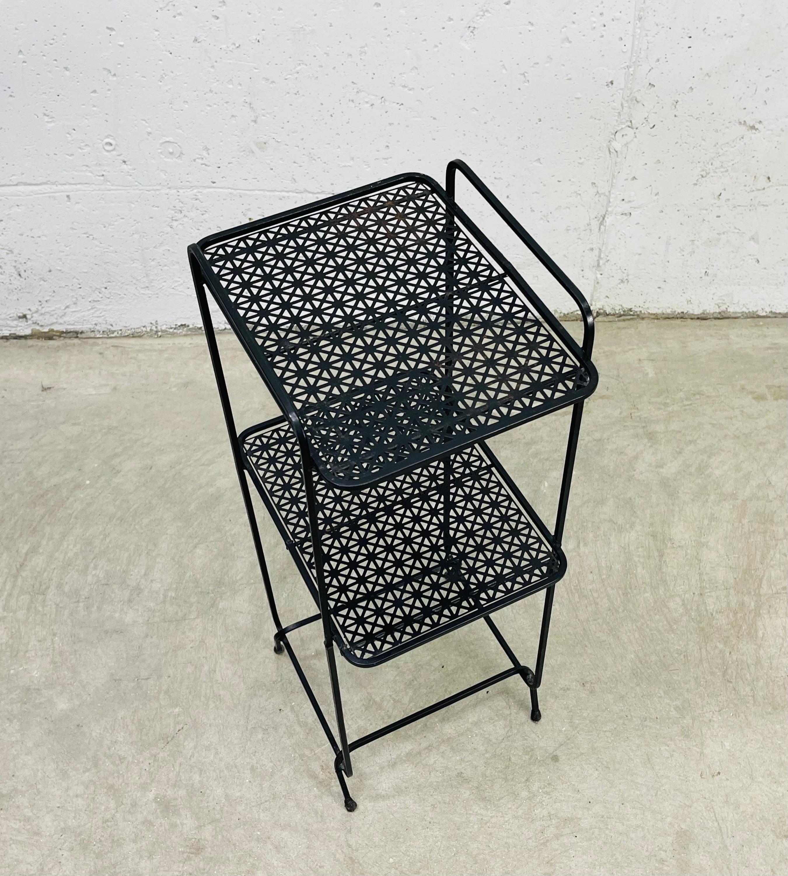 Vintage 1960s black metal side table with two mesh shelves. The bottom shelf is 15”H. No marks.