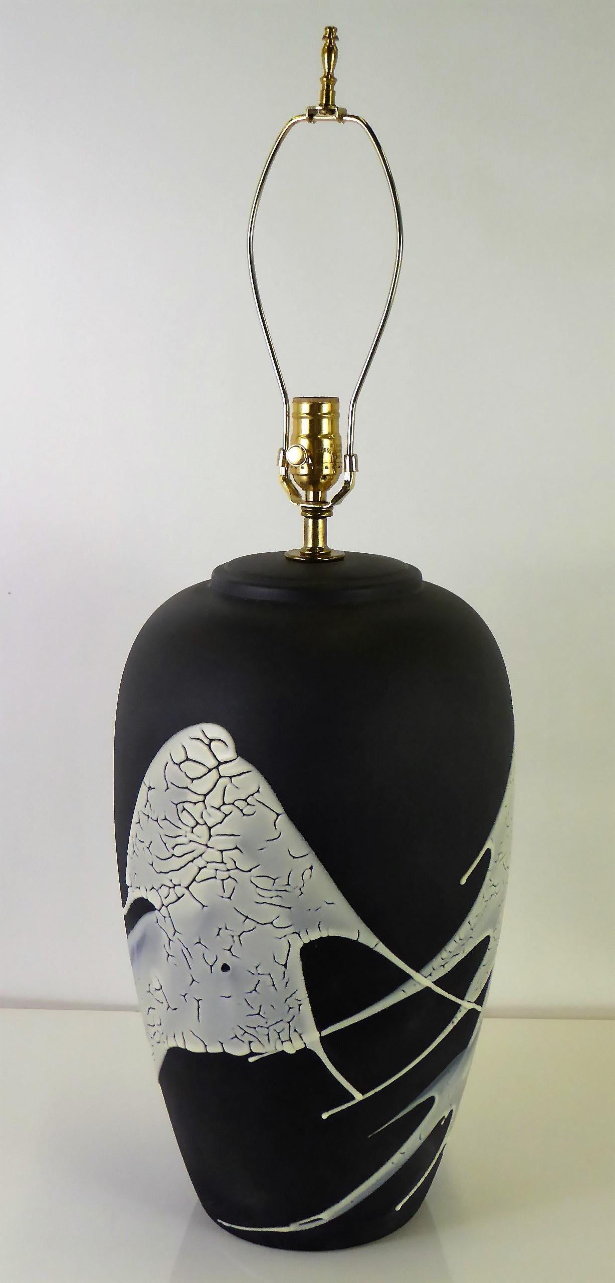 1960s lava glaze ceramic table lamp with a matte black finish and splashes of white lava glaze. An oil jar shape, it has been rewired and with a new brass UL three level socket. Takes medium base bulbs.
Measurements: 10 in. diameter x 20 in. high