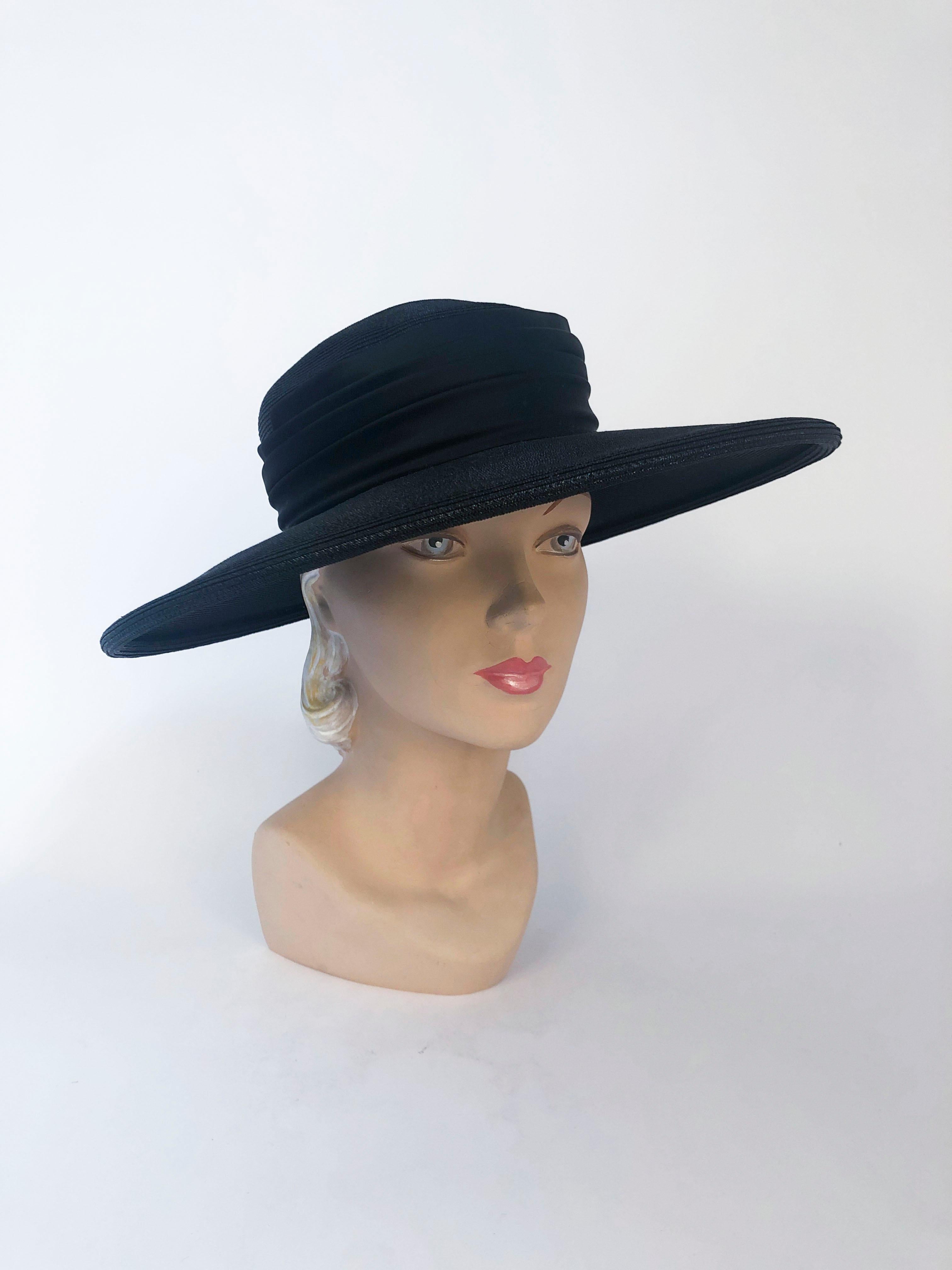 1960's Black coated Straw Hat with Wide Tiered Satin Band and oversized bow on the back of the wide brim. The satin band has tiered effect that meets at the back to created the base of the bow.