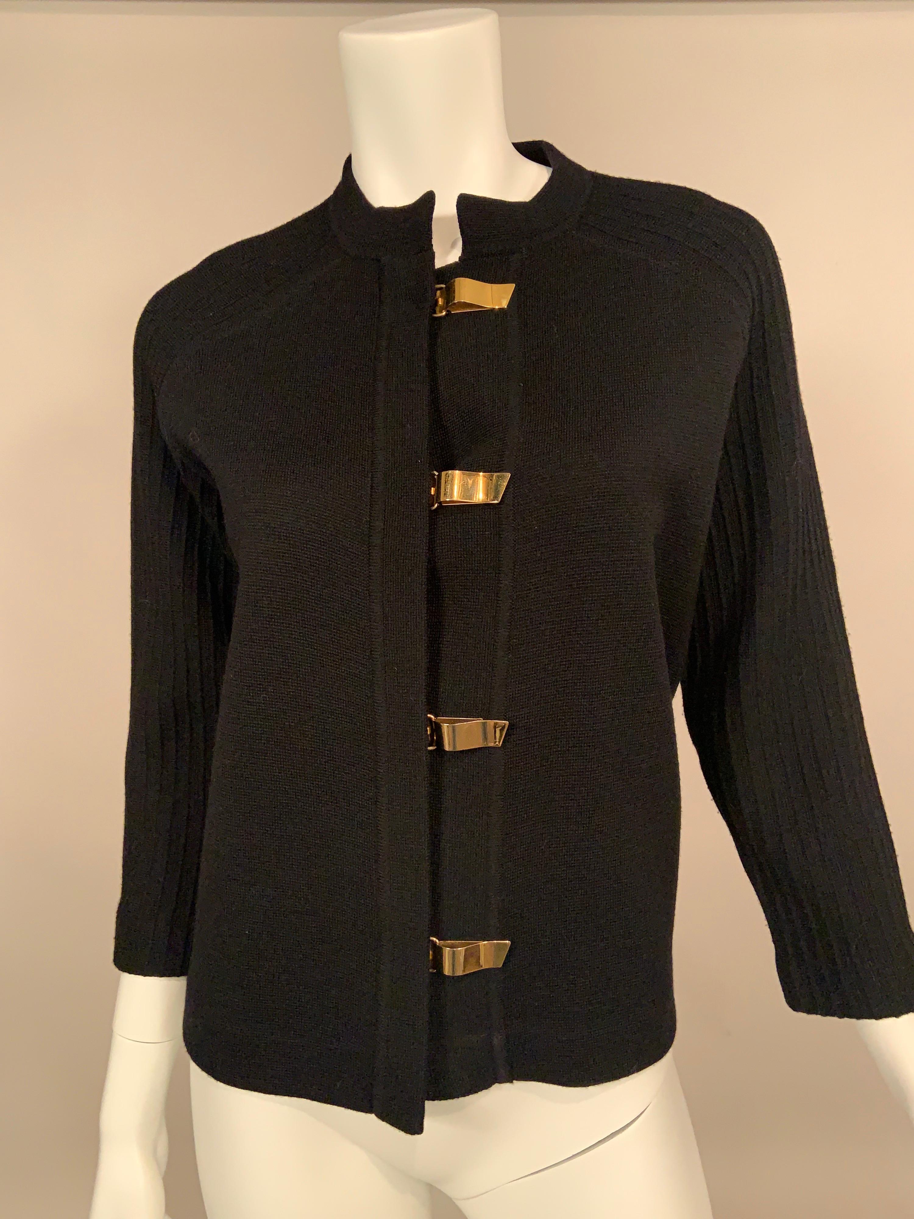 This black wool cardigan sweater has so many interesting details!   The sweater has a collar and front placket with very interesting gold toned toggles for closures, reminiscent of Bonnie Cashin designs.  The body of the sweater is a flat knit and